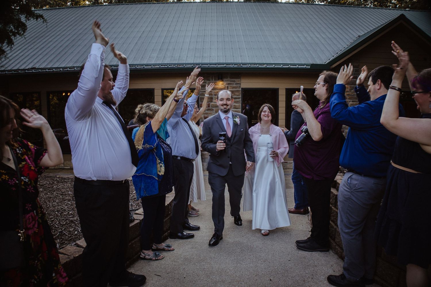 Wedding guests dance together at an outdoor reception under a covered patio area.