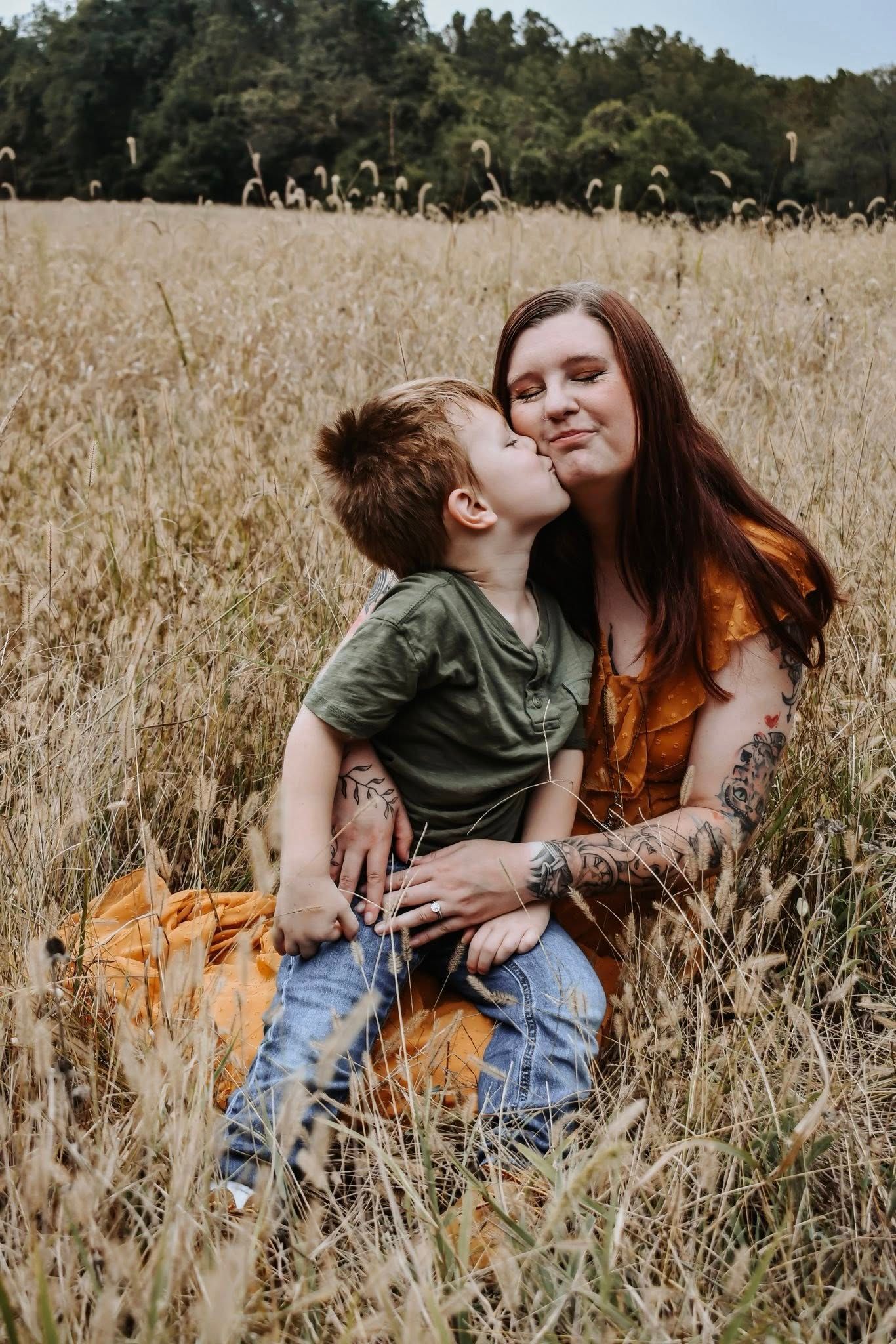 A tender moment shared between two people sitting together in a golden wheat field on a sunny afternoon.