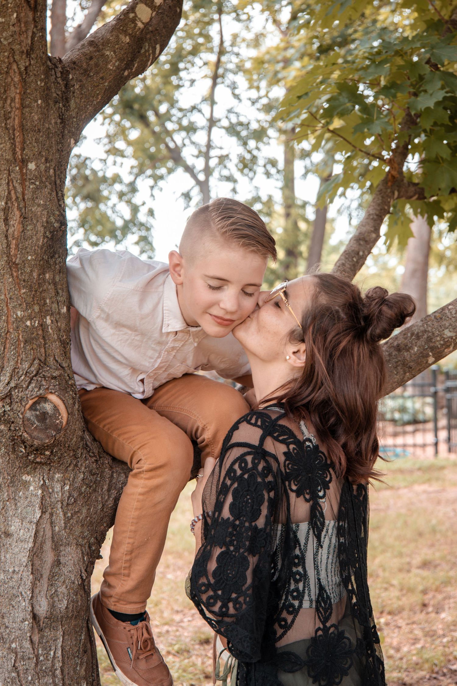 A tender moment shared between two people among autumn trees in a park setting.
