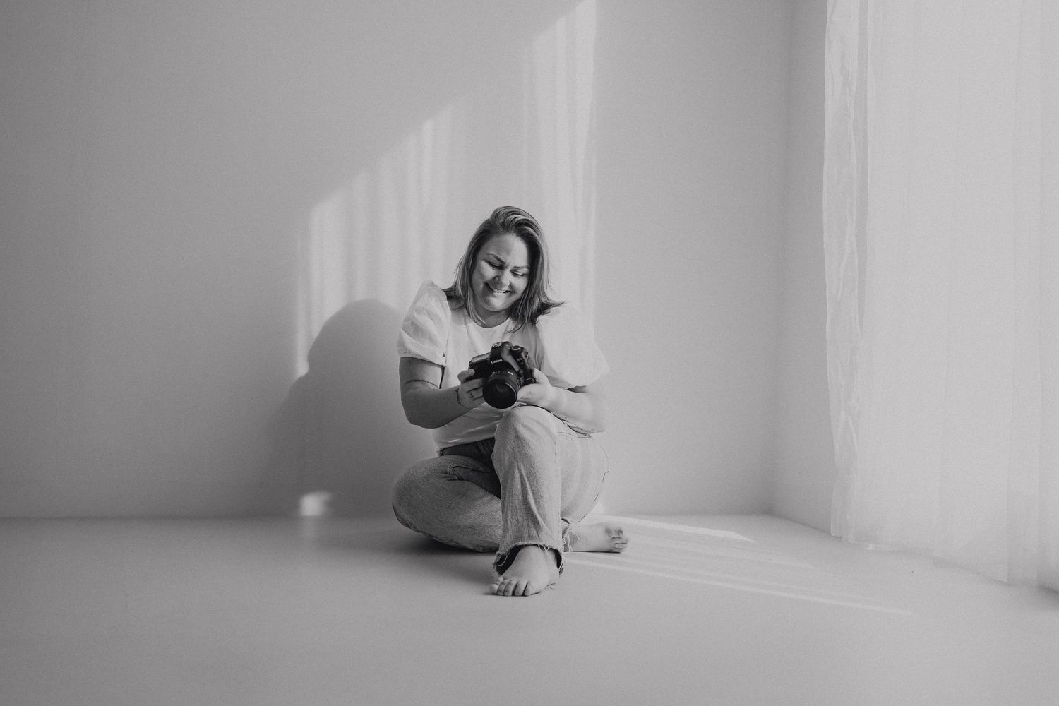 A black and white photo series showing a person in white curled up against a wall in various contemplative poses.