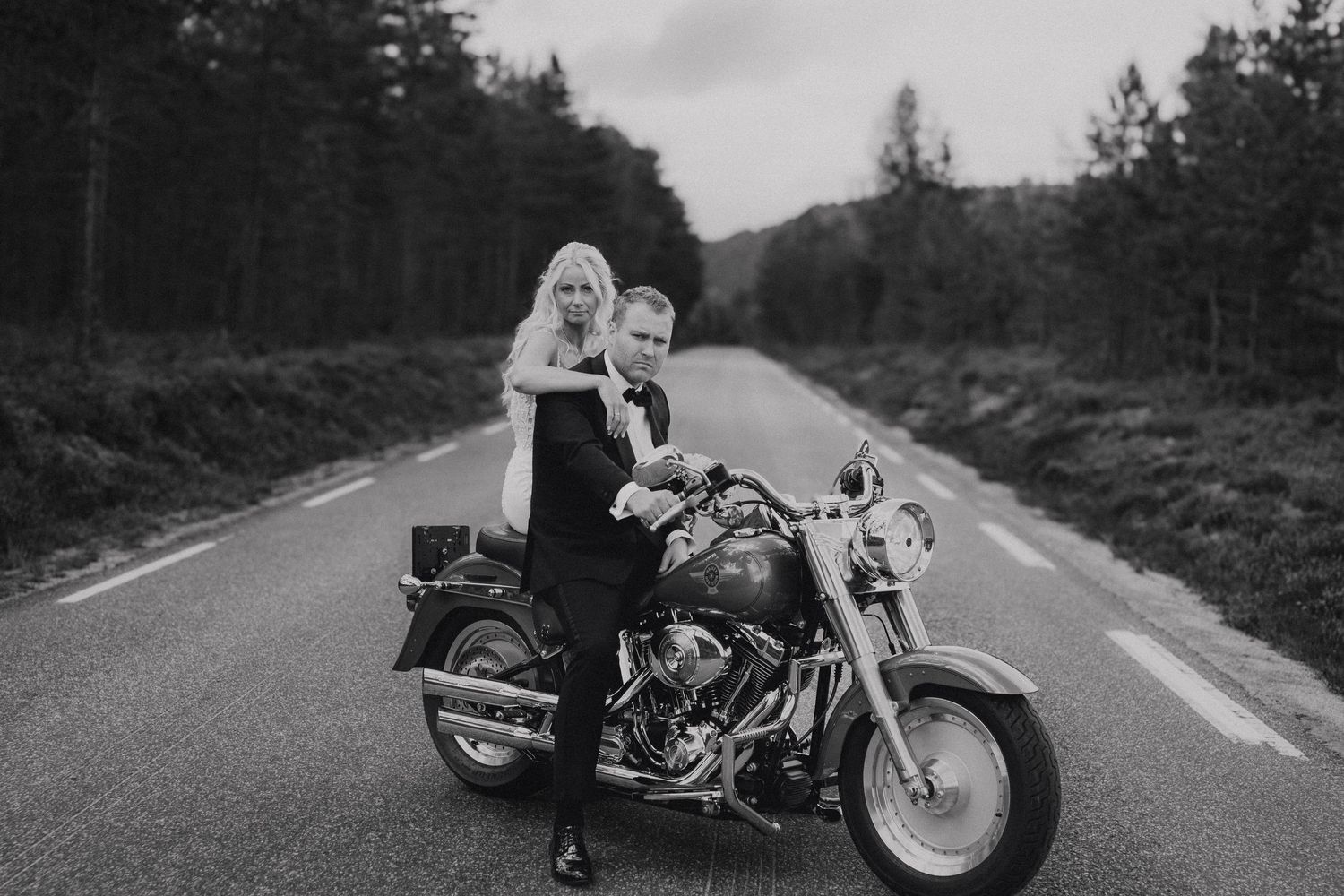 Motorcycle parked on winding forest road during cloudy day.