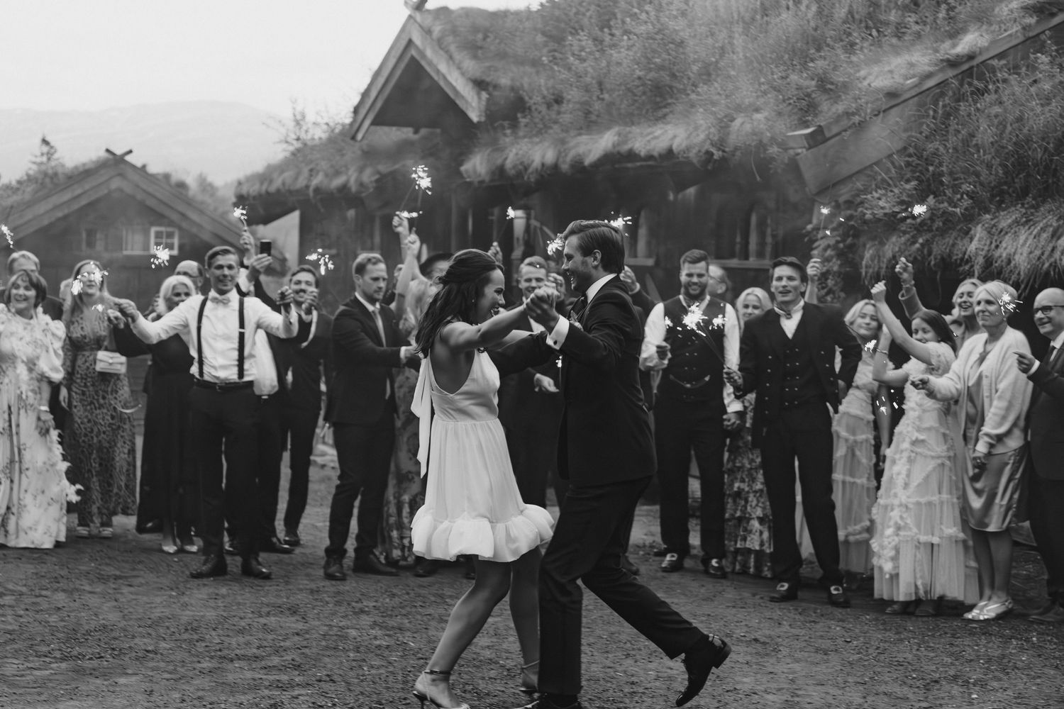 A vintage black and white photograph shows a couple dancing at an outdoor celebration while guests watch from the sides.