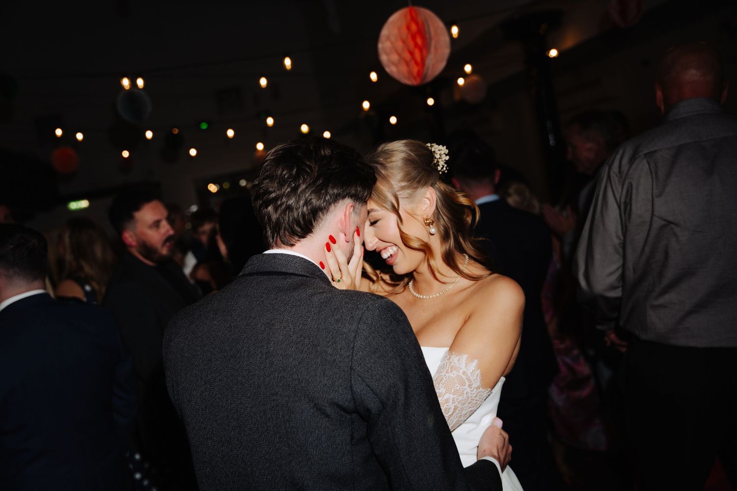 A couple shares a romantic kiss on the dance floor during a dimly lit wedding reception celebration. Glasgow Engine Works
