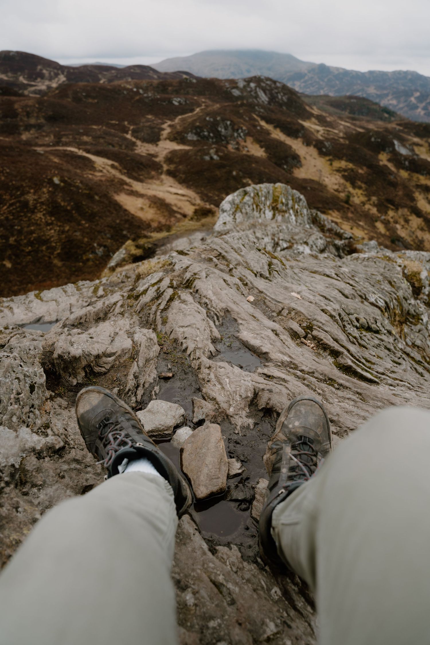 A hiker's perspective looking down at their boots on a rocky mountain summit.