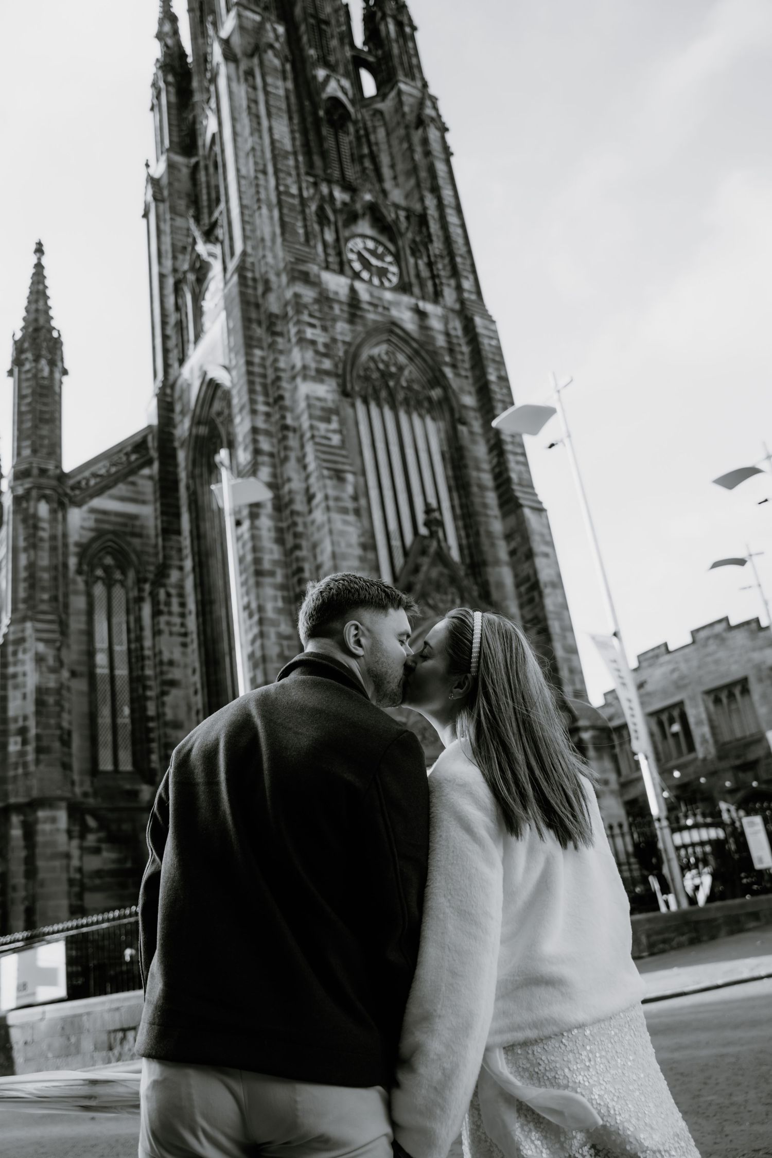 A couple stands in front of Edinburgh's historic Scott Monument captured in a series of black and white photographs.