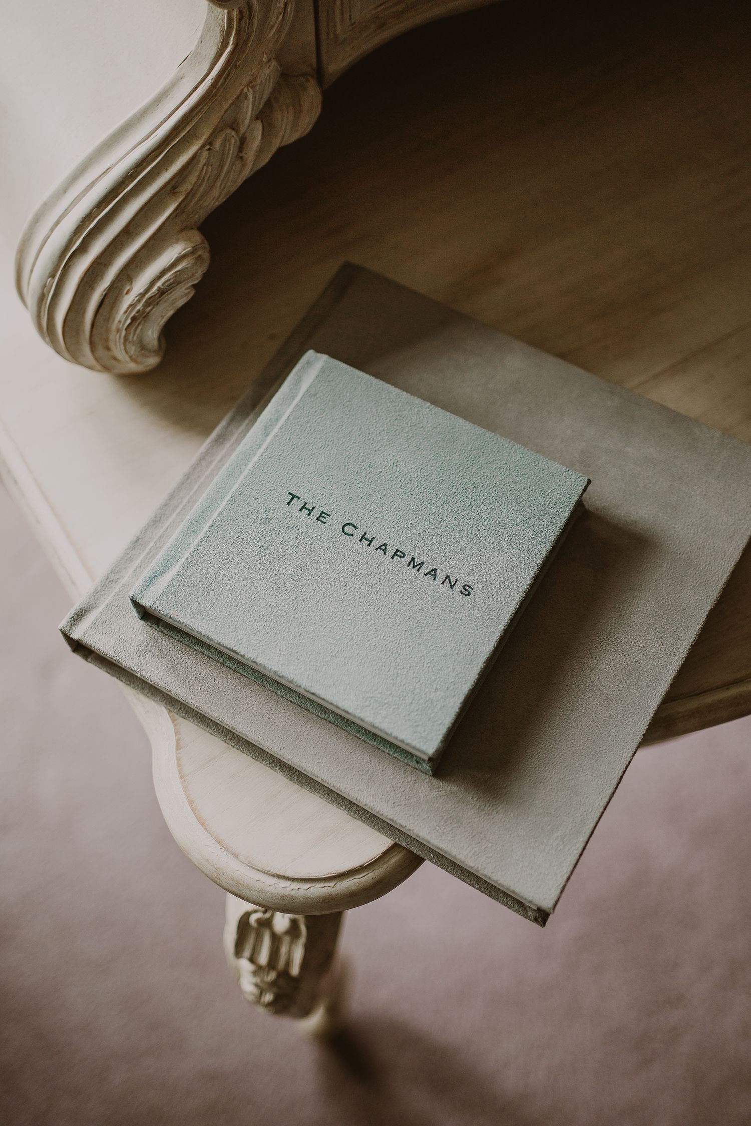 Gray photo album resting on an ornate vintage table with carved details.