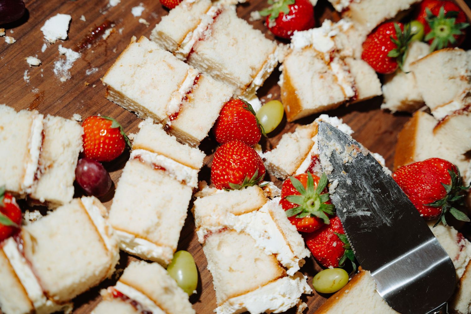 A close-up view of sliced tres leches cake topped with fresh strawberries and whipped cream on a wooden surface. Glasgow Engine Works