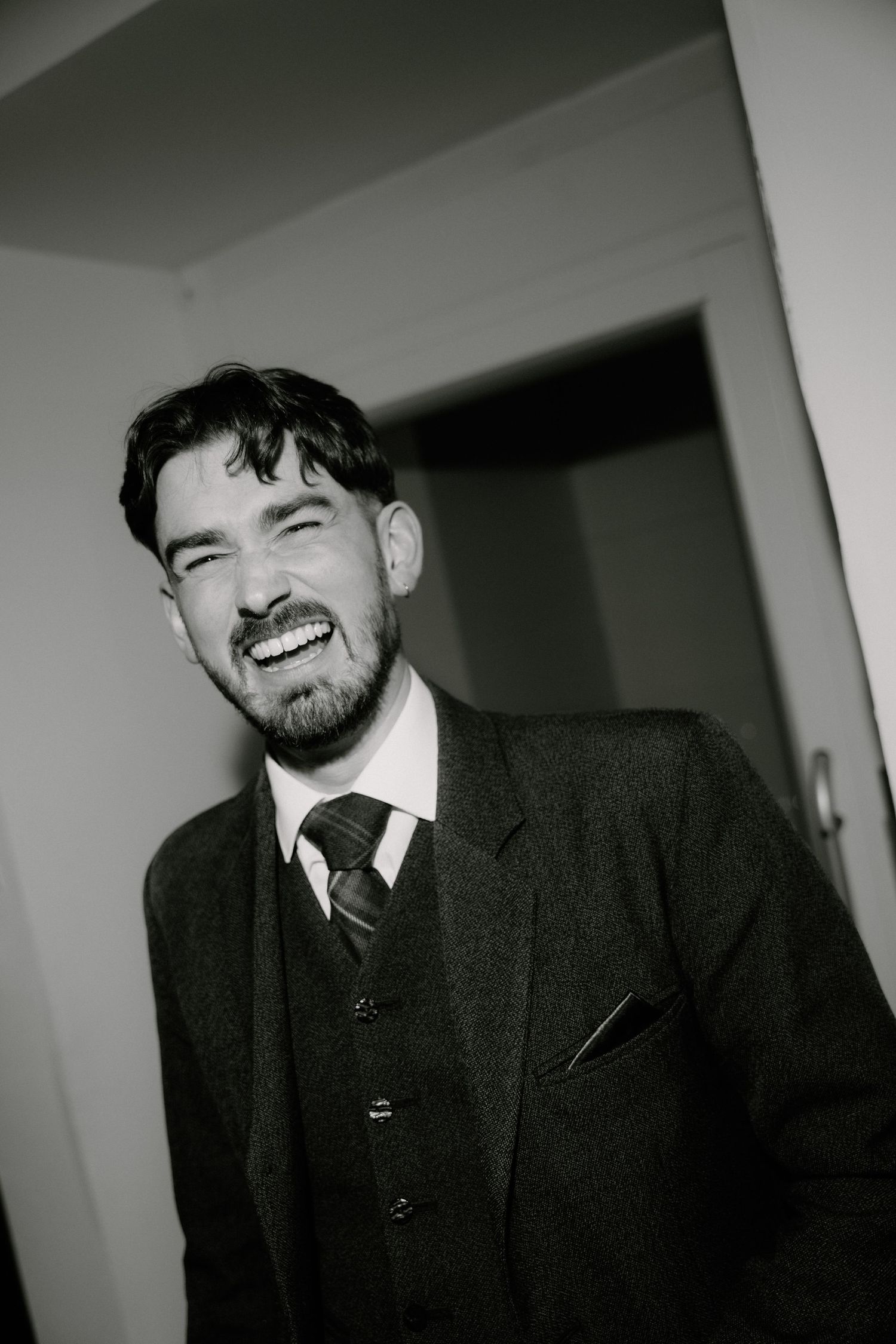 Black and white photo series showing four similar poses of someone in a dark suit smiling at the camera.