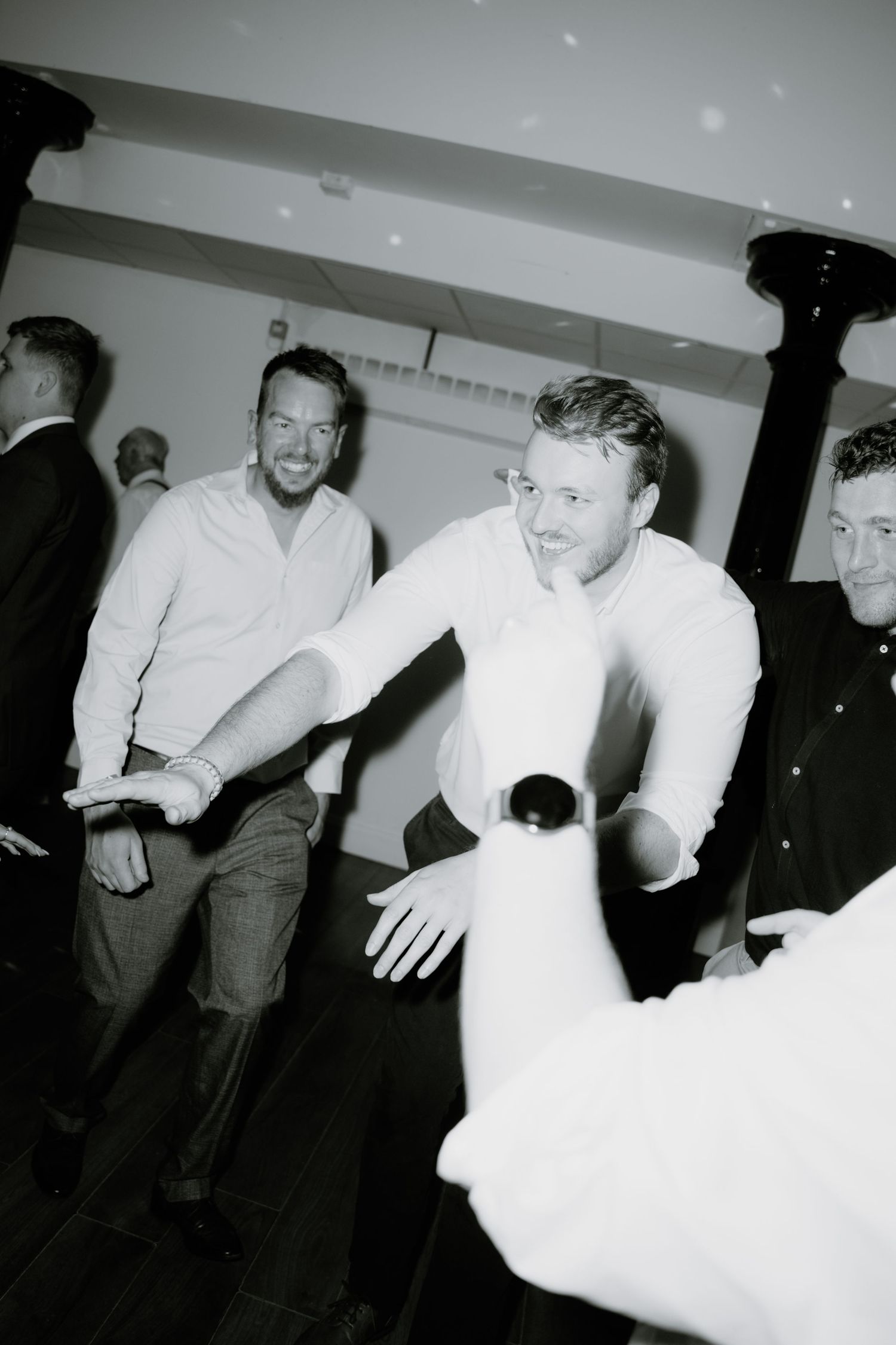 A black and white candid photo showing people in casual attire interacting at what appears to be a social gathering. Glasgow Engine Works
