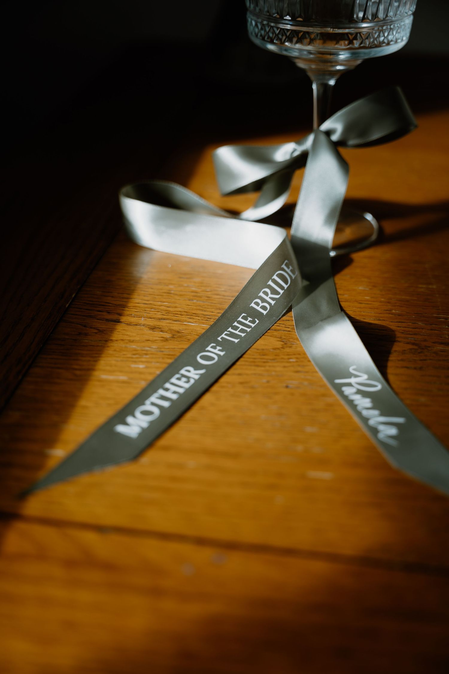 Closeup shots of a dark ribbon with text printed on it lying on a wooden surface in dramatic lighting.