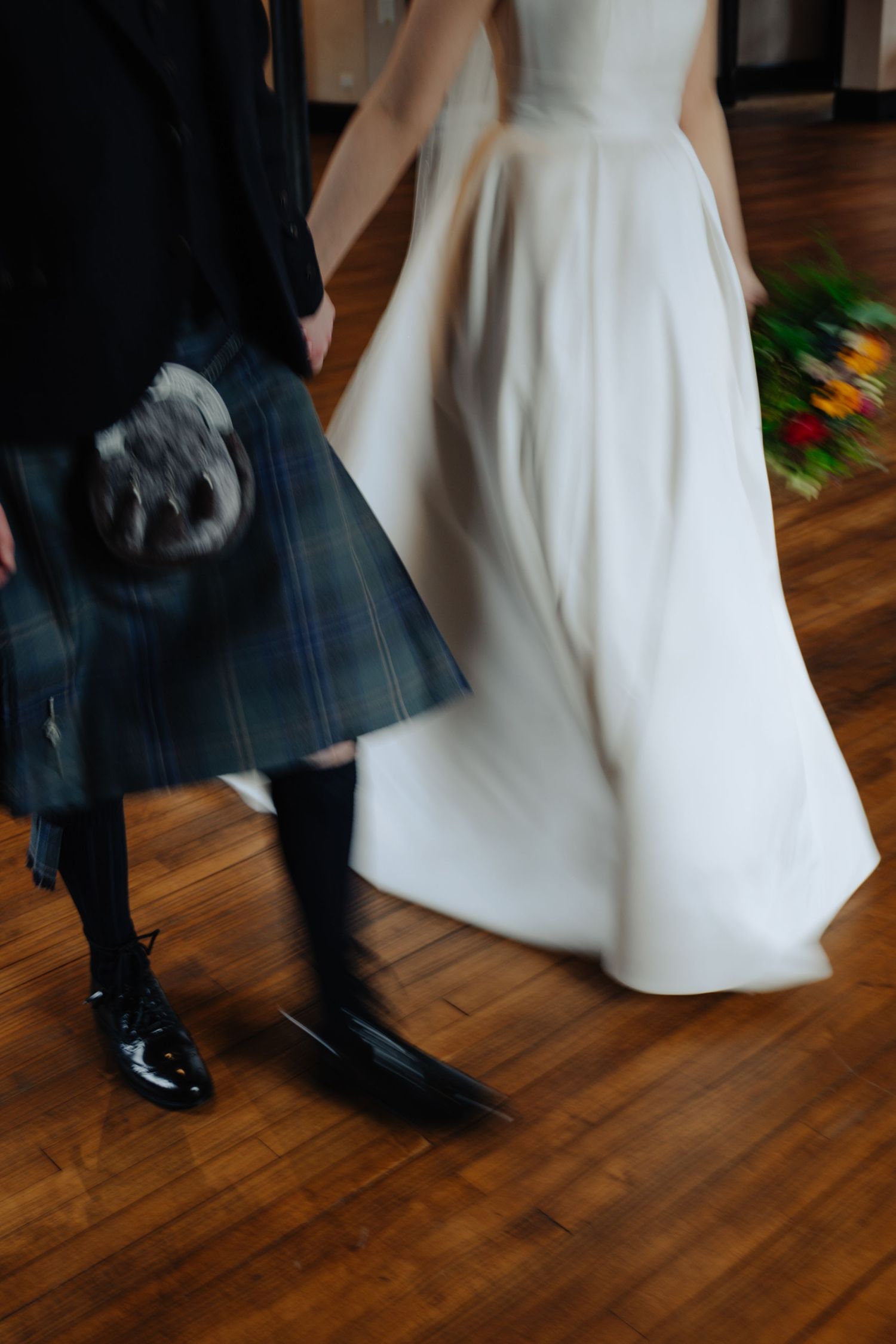 Feet of a couple dancing on a wooden floor, with a flowing white gown and dark suit visible. Glasgow Engine Works