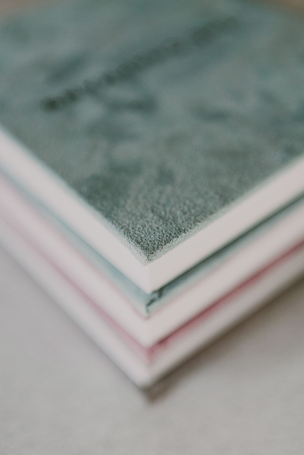 Macro shot of stacked books showing textured covers in green and pink tones.