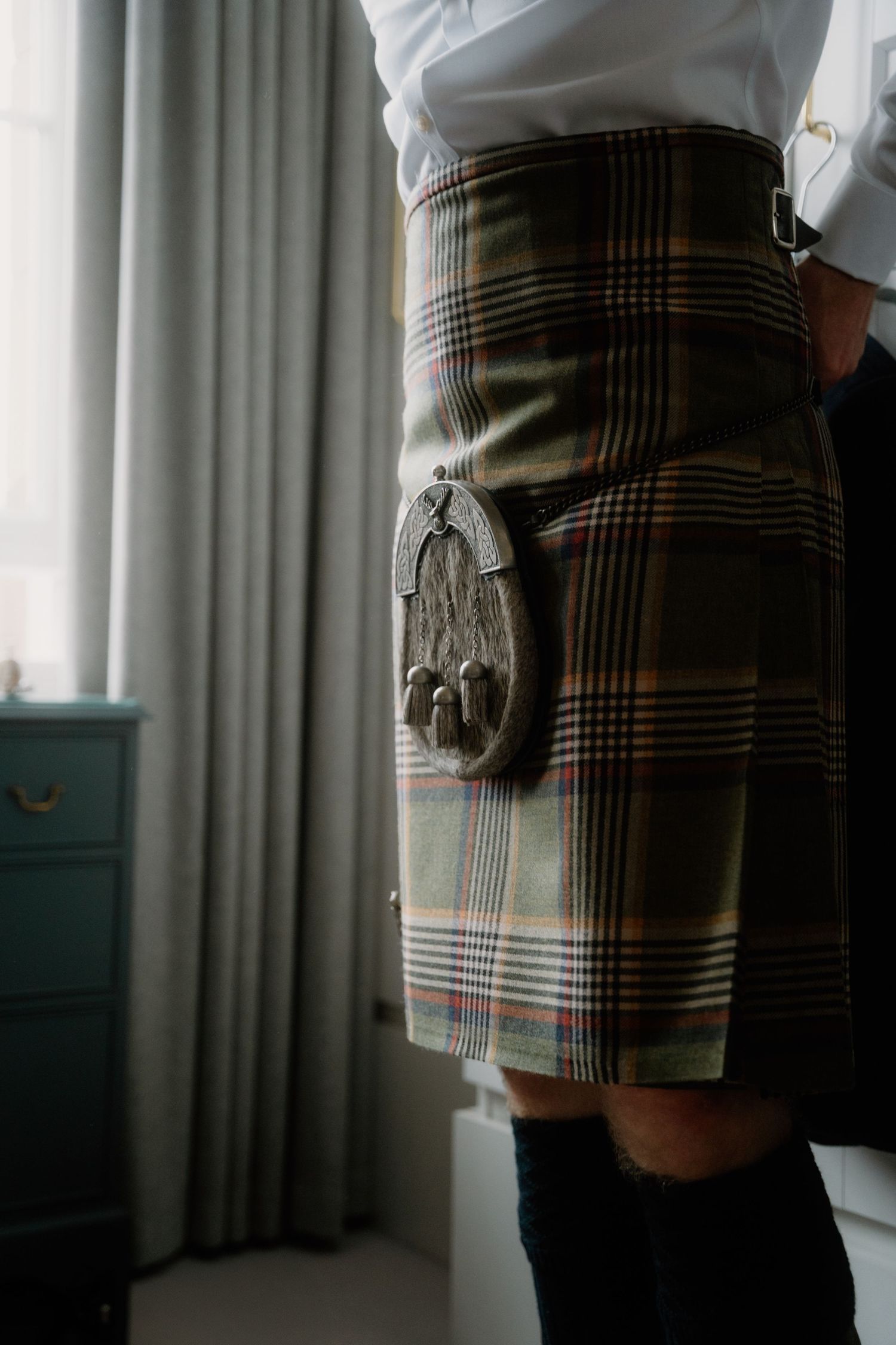 Close-up of a traditional plaid kilt with sporran attachment showing detailed tartan pattern and craftsmanship.
