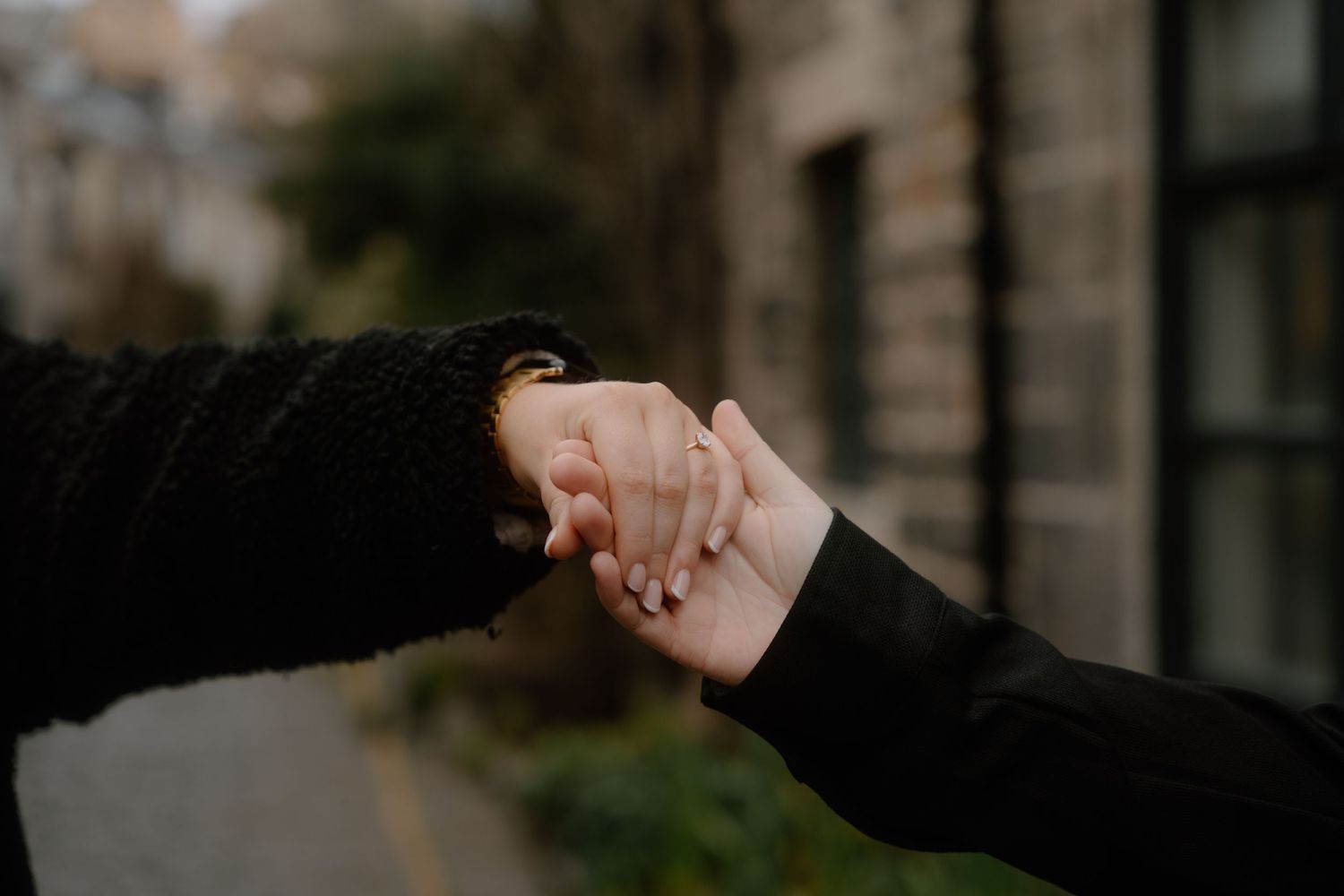 Close up of hands reaching out to hold each other against urban background.