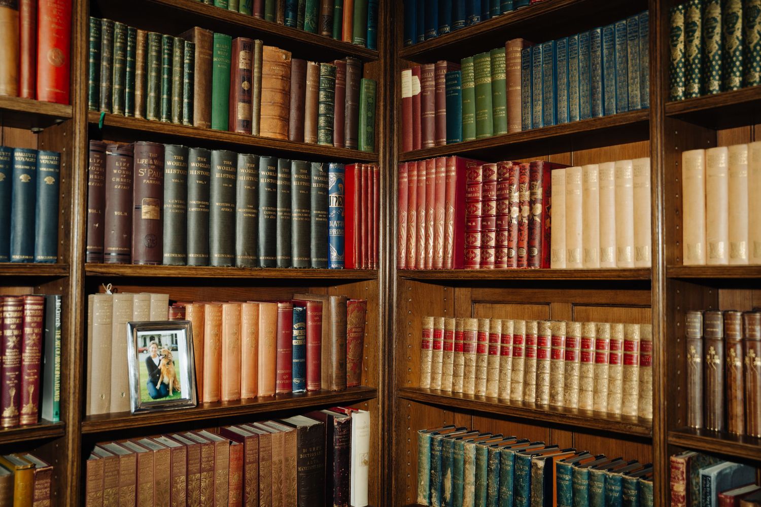 Dundas Castle Wooden bookshelves filled with vintage leather-bound books line the walls of an elegant library interior.