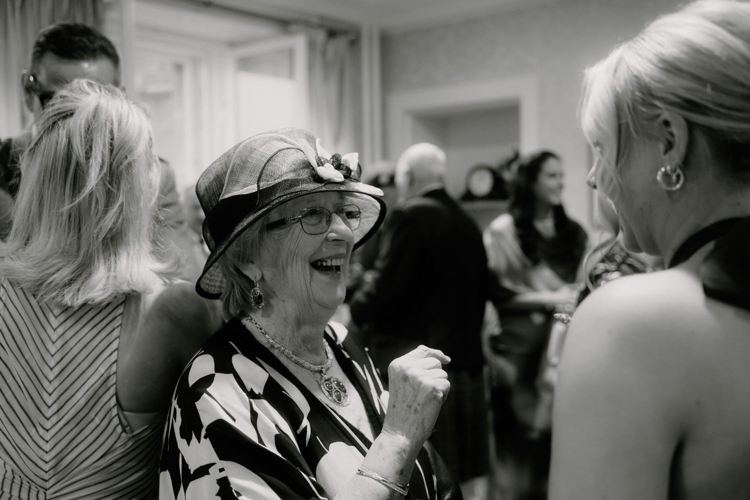A black and white photograph of guests mingling at an elegant social gathering.