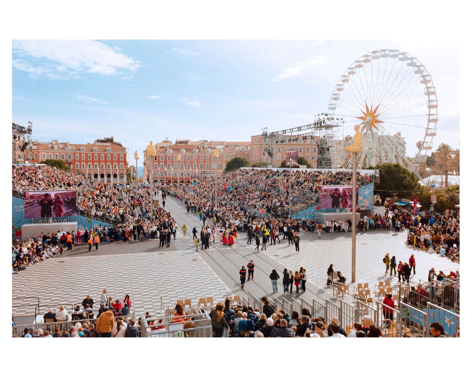 Aerial view of large carnival celebration in Nice city square with Ferris wheel and crowds.
Nice Carnival