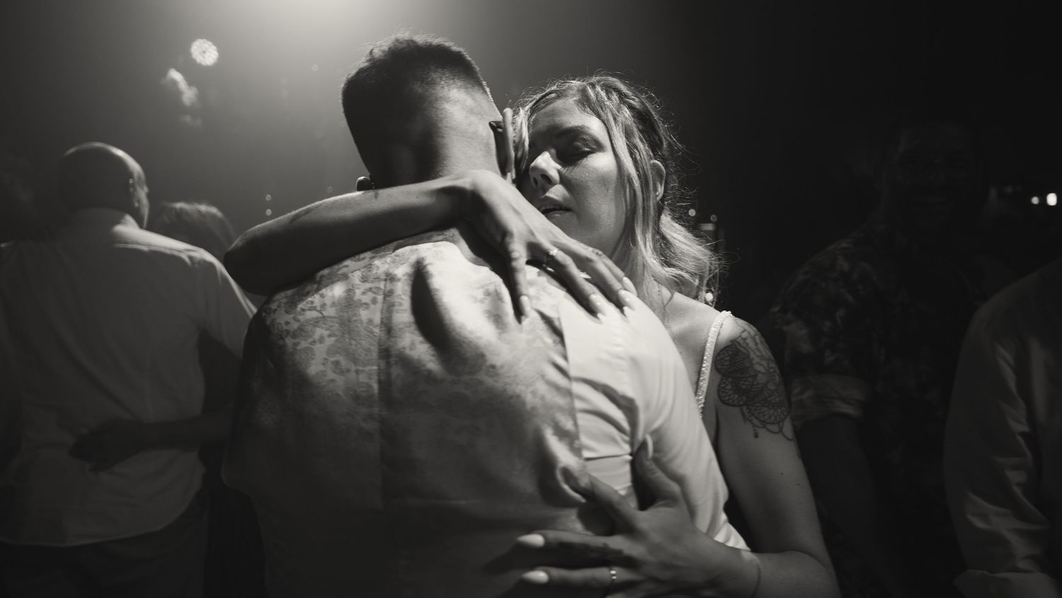 Black and white intimate photo of a bride and groom embracing closely during a romantic wedding dance.