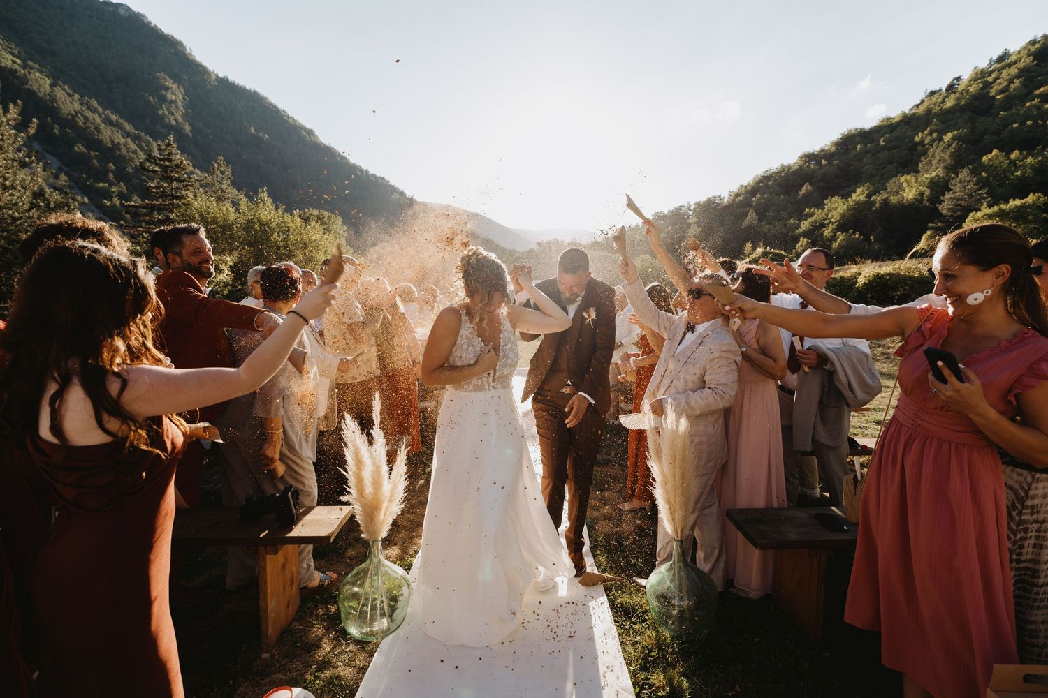 Bride and groom celebrated by guests throwing confetti at golden hour outdoor mountain wedding.