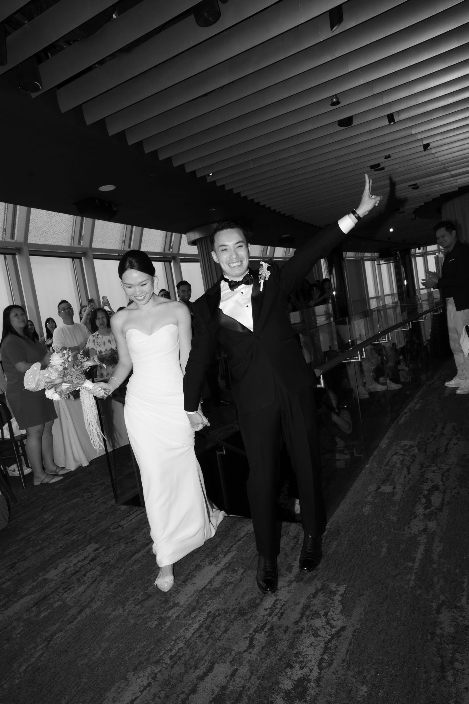 Black and white photo of a joyful bride and groom walking down the aisle after their wedding ceremony.