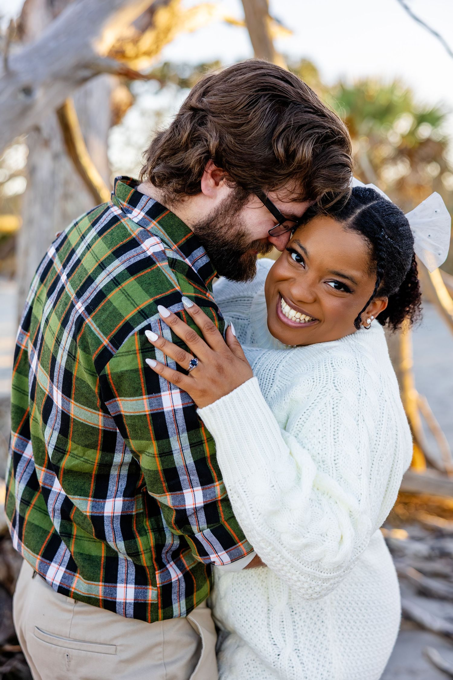 Couple posing for engagement photos on Driftwood Beach during winter.