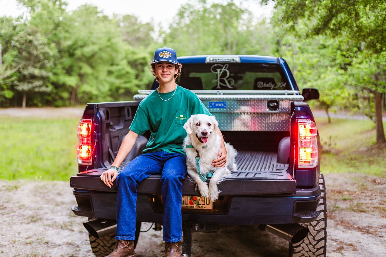 Senior boy sitting with dog on truck at Alpine Grove during sunset portraits.