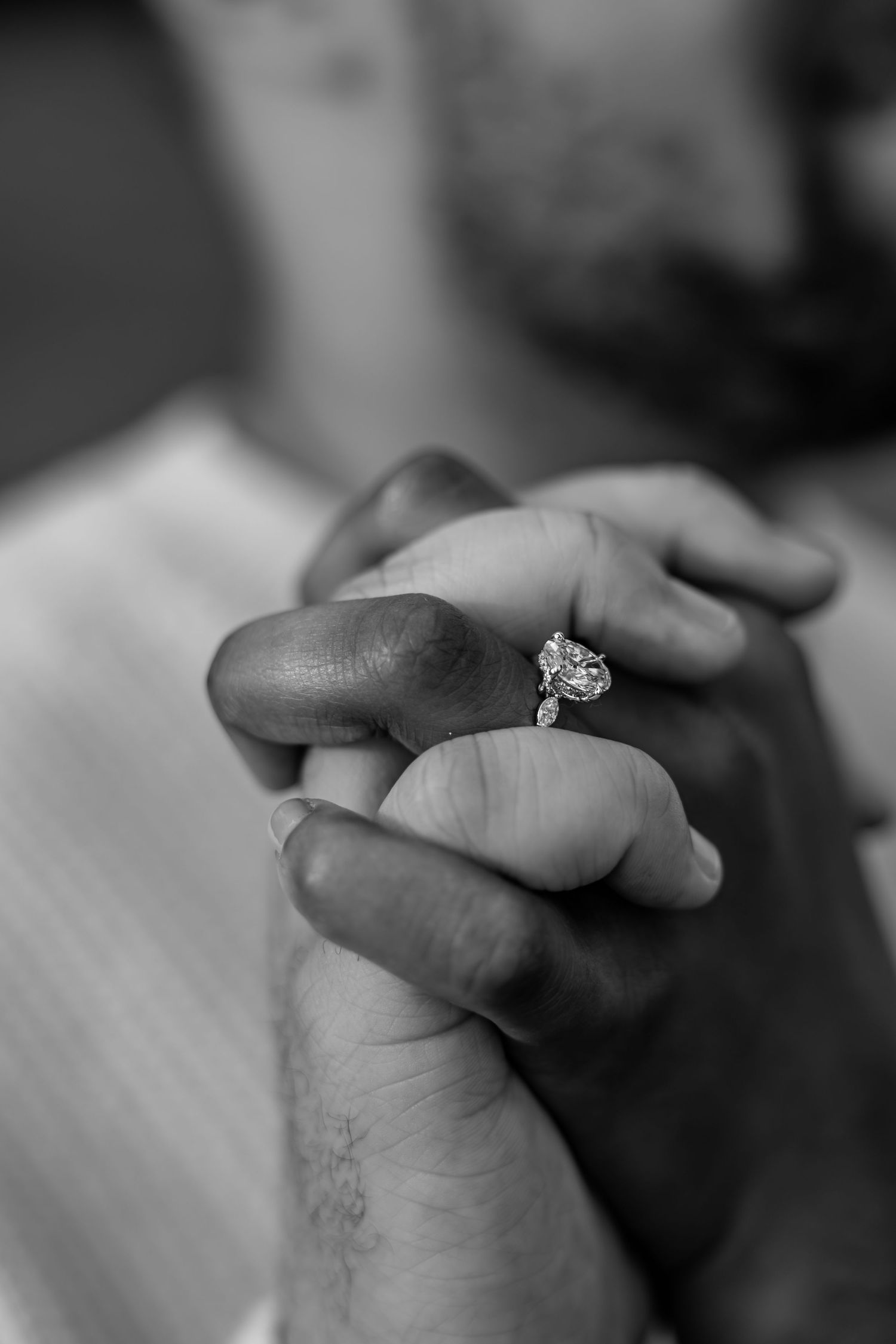 Detail photo of recently engaged couple holding hands, showcasing the stunning diamond engagement ring.