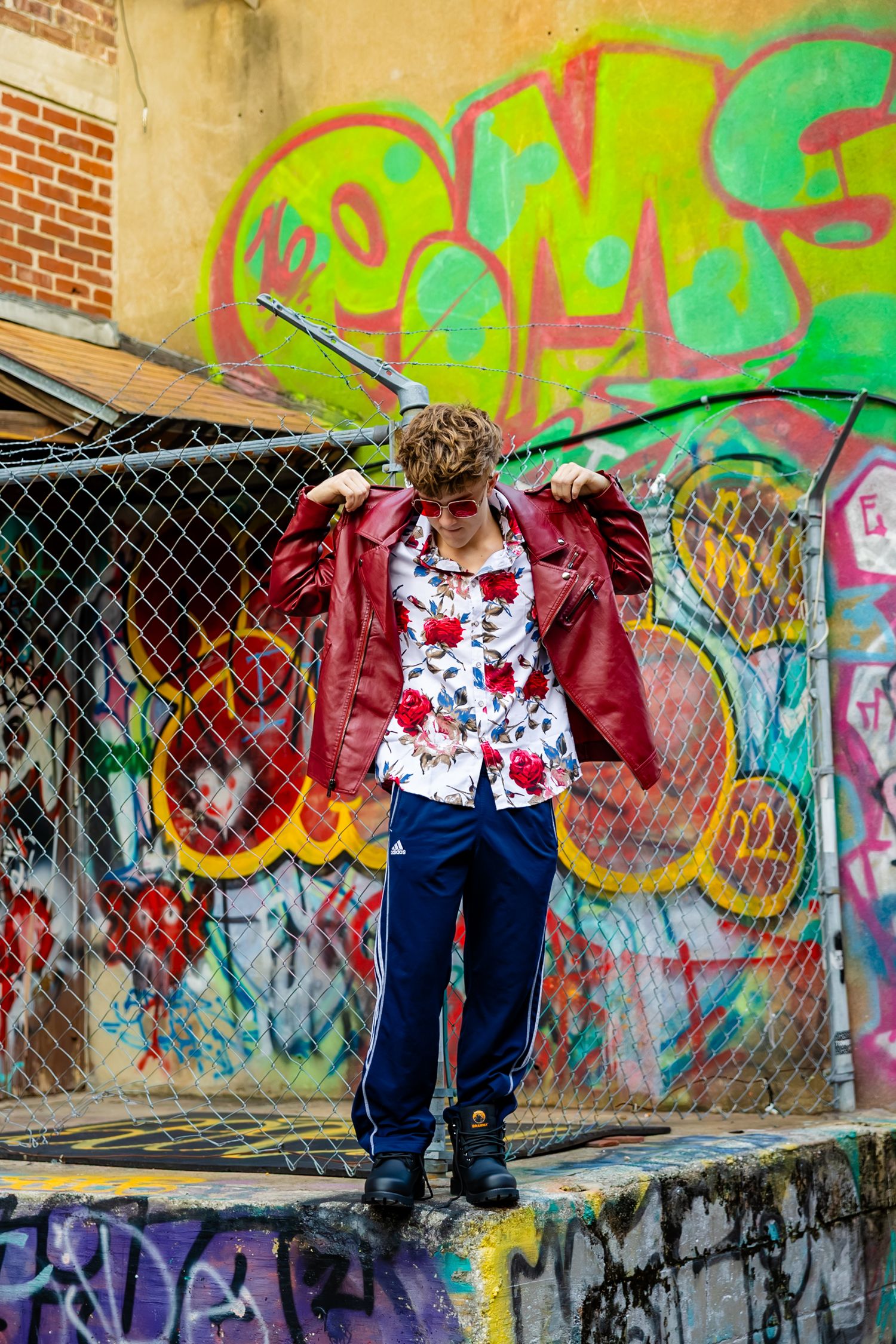 Senior boy in Fight Club inspired outfit posing against vibrant graffiti wall in Downtown Jacksonville.