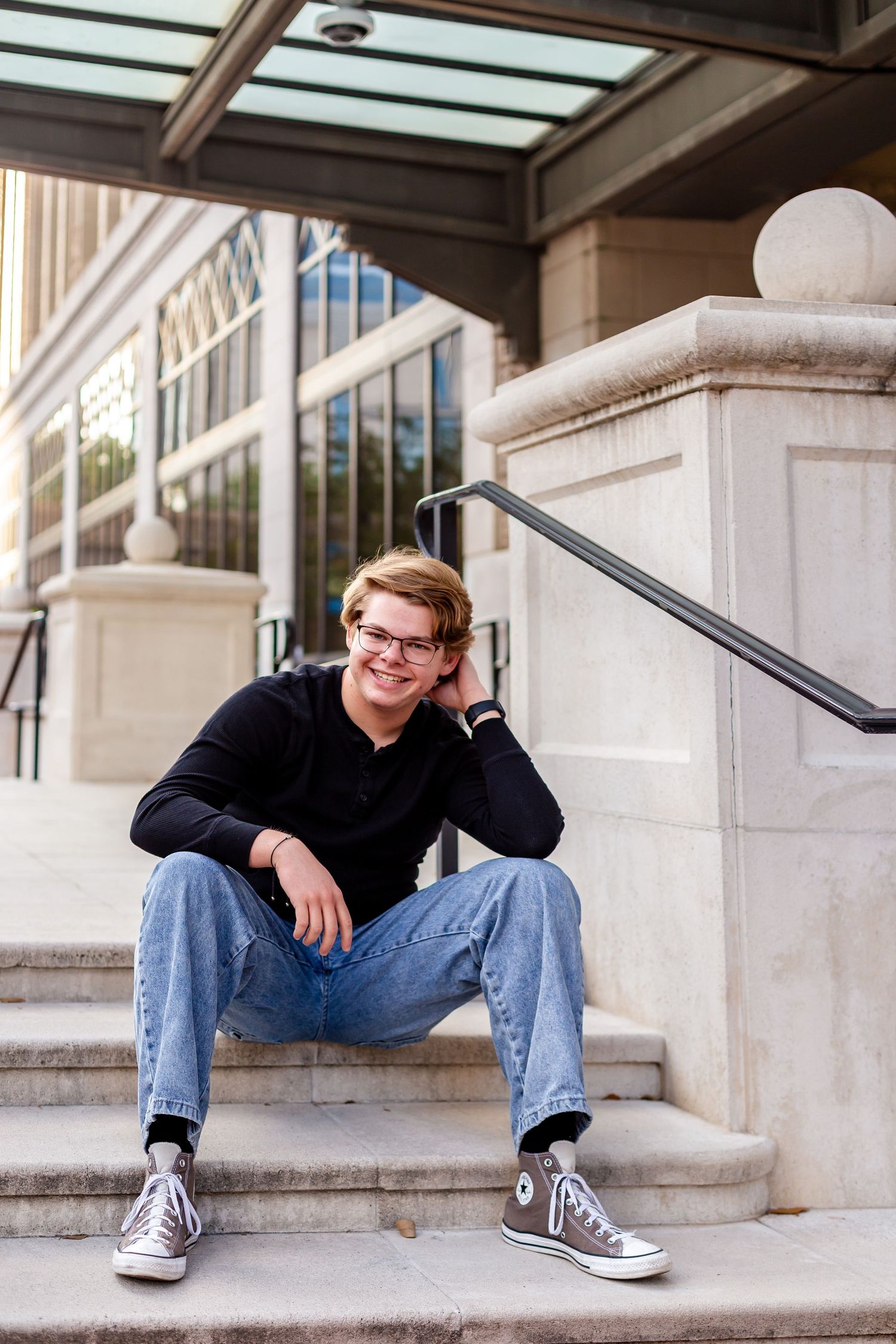 Senior guy sitting and posing on steps near James Weldon  Johnson Park during golden hour portrait session.