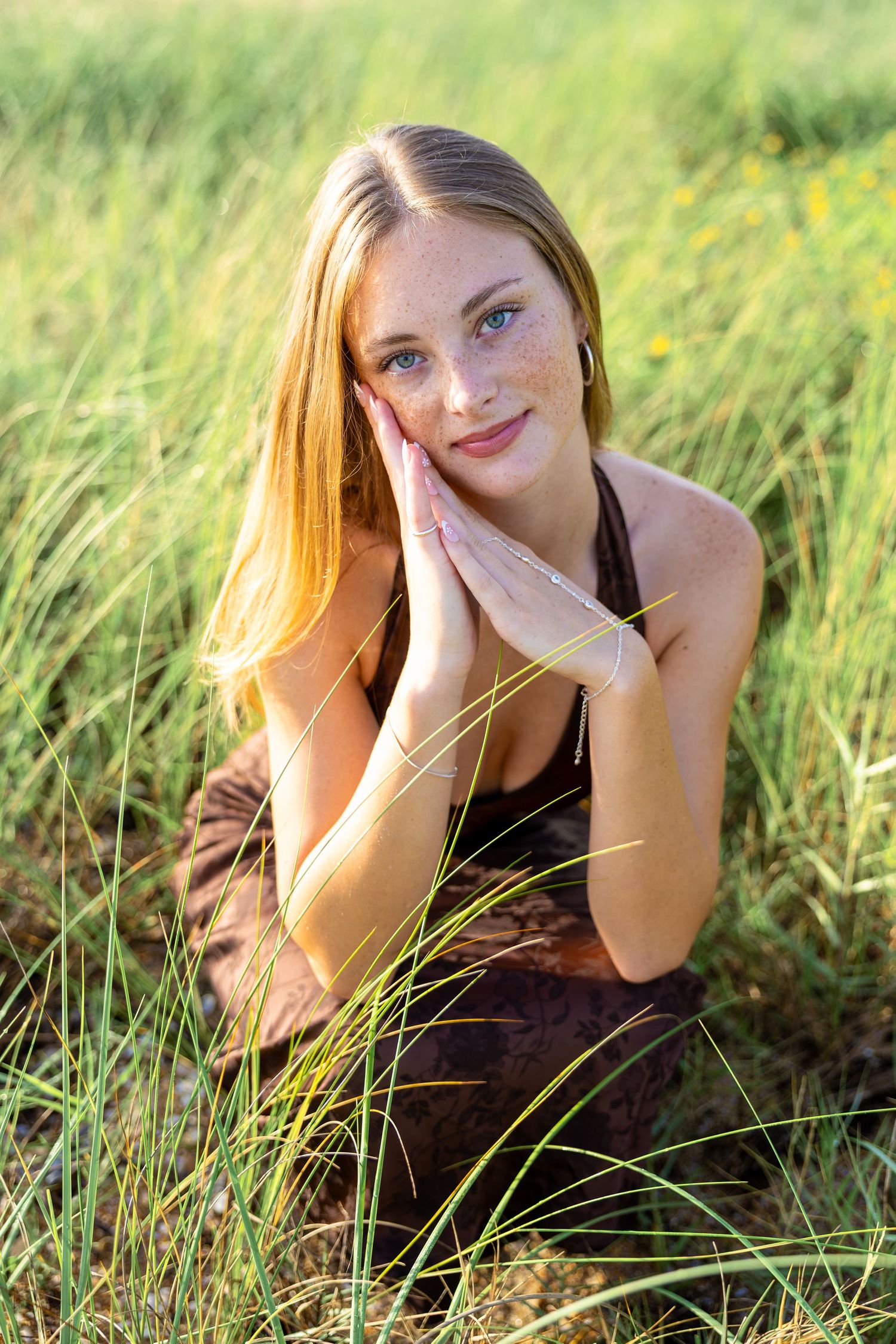 Senior girl sitting in sunlit Ponte Vedra Beach grass on a warm summer day.