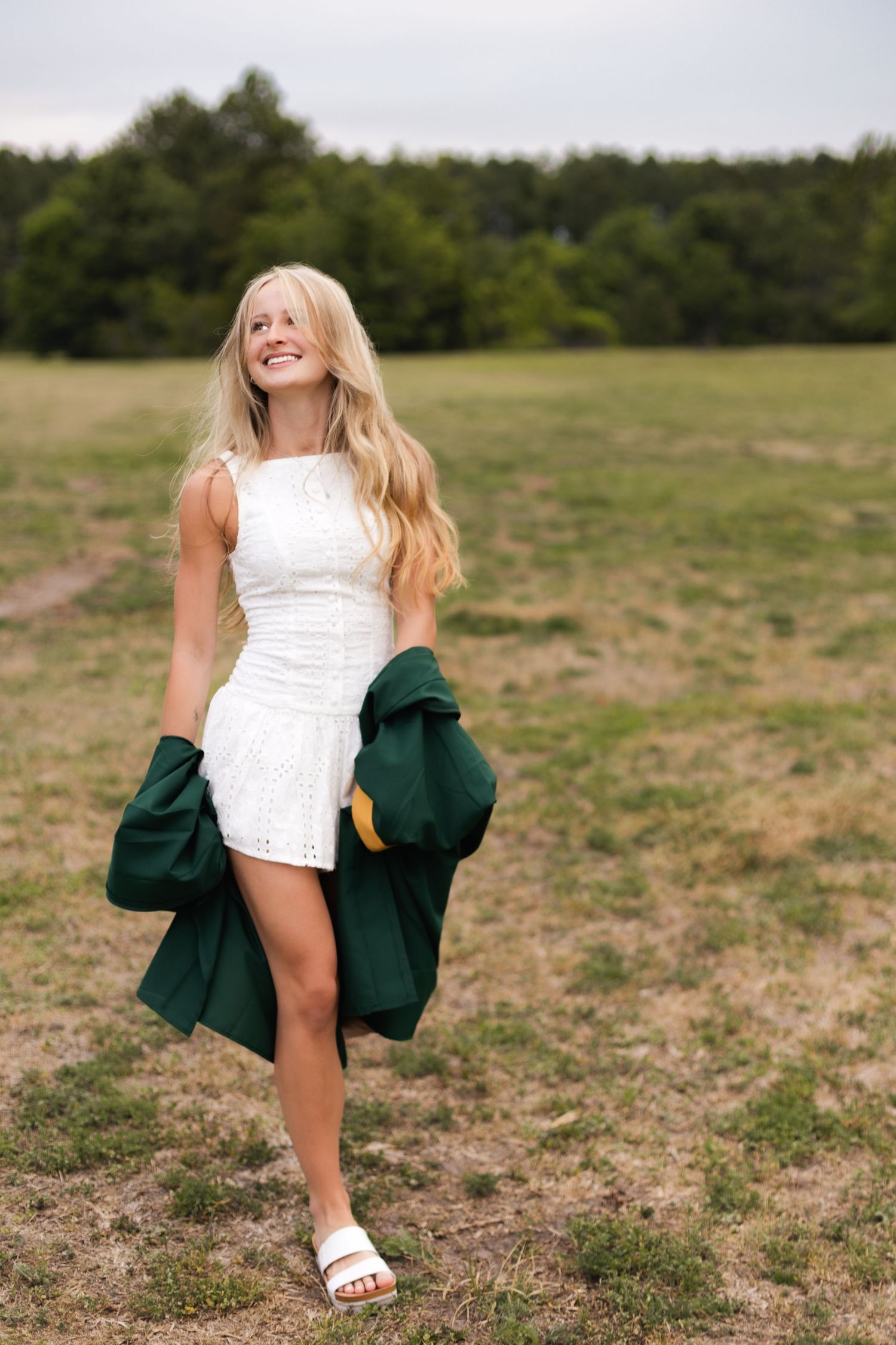 High school senior smiling while walking through a grassy field at Sheffield Regional Park in Jacksonville, Florida.