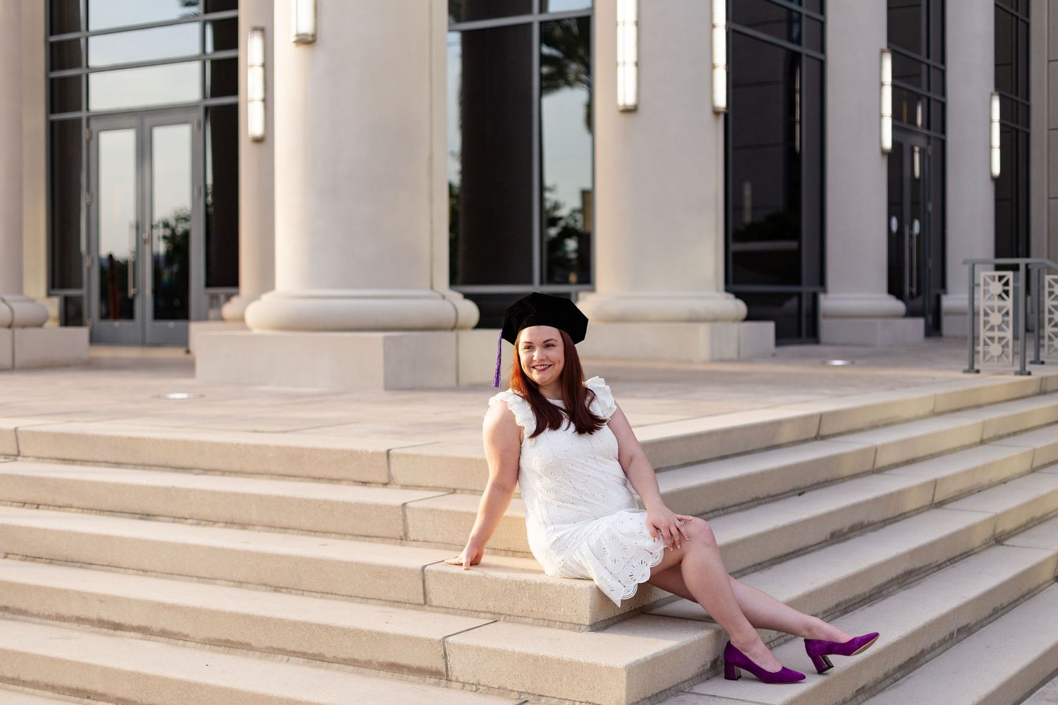 Woman sitting on Duval County Courthouse steps outside in graduation attire.