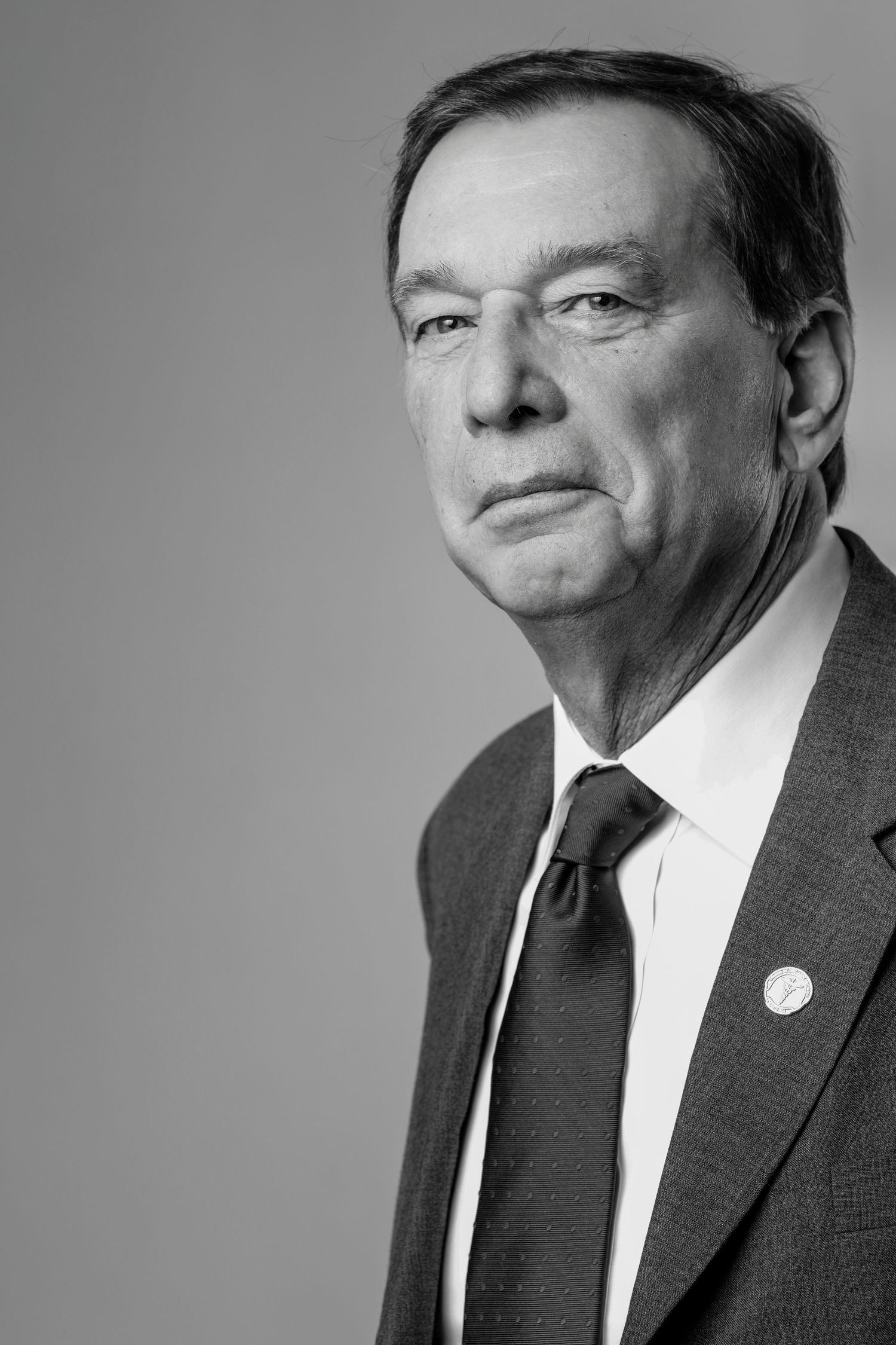 Black and white portrait of senior businessman in suit and tie looking serious.