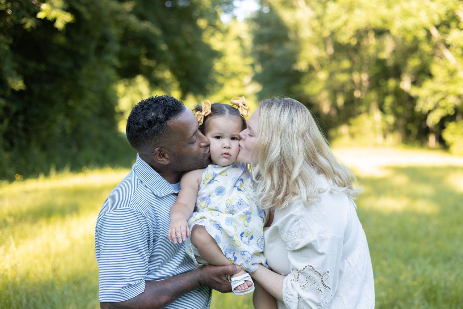 Family portrait of parents kissing toddler outdoors, Huntsville Alabama family photographer