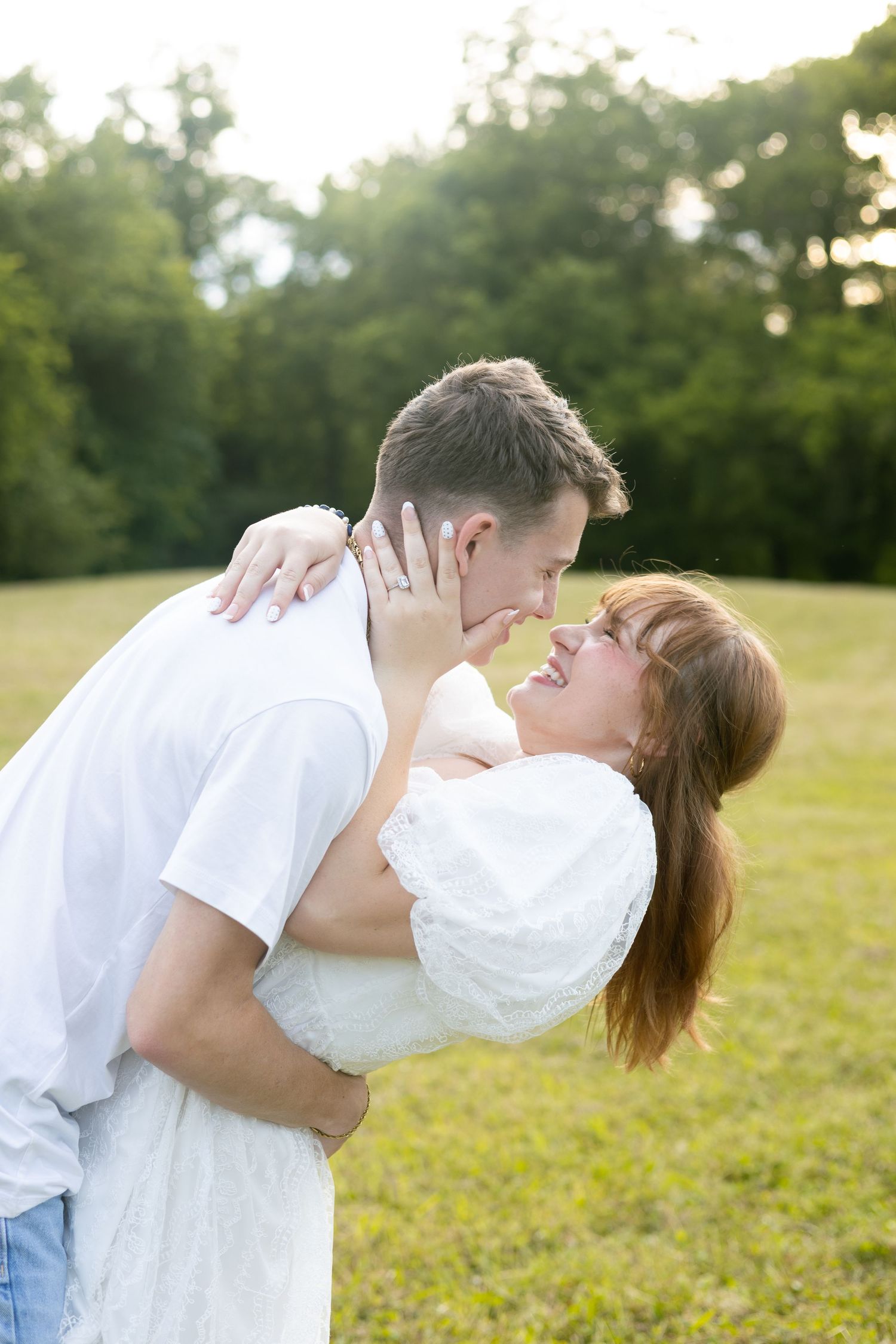 Couple sharing a kiss outdoors in a green field, Huntsville Alabama engagement photographer