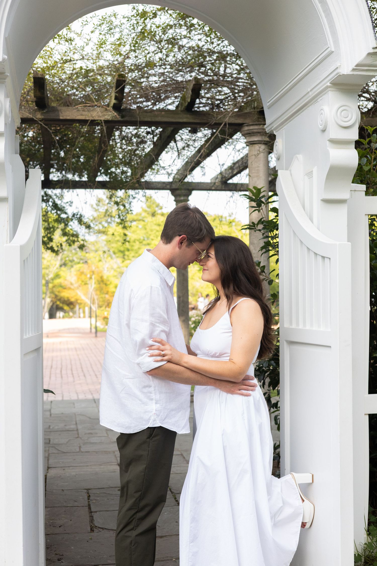 Couple embracing under a floral pergola, Huntsville Alabama engagement session