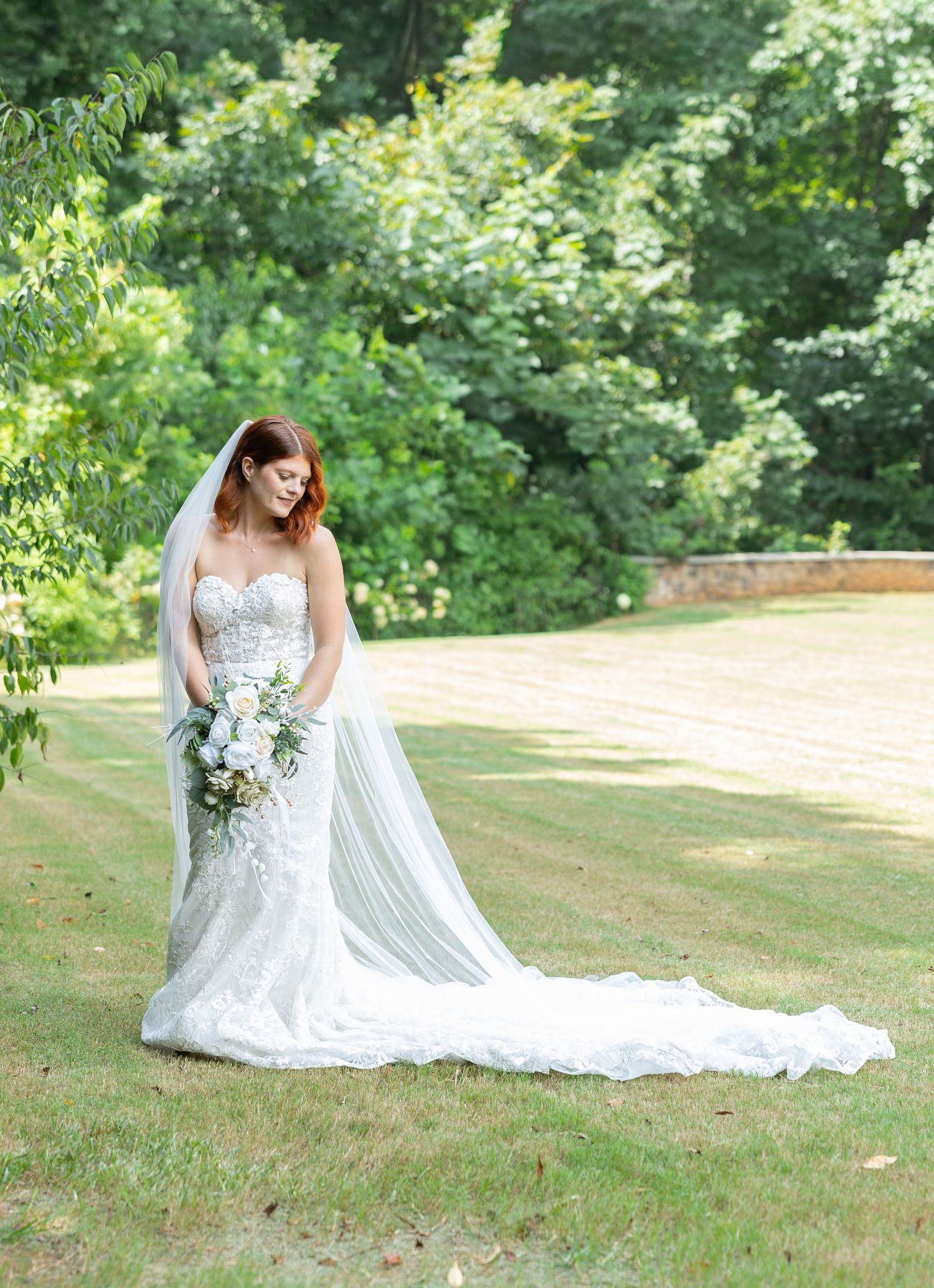 Bride in lace wedding gown holding bouquet on a garden lawn, Huntsville, Alabama wedding photographer