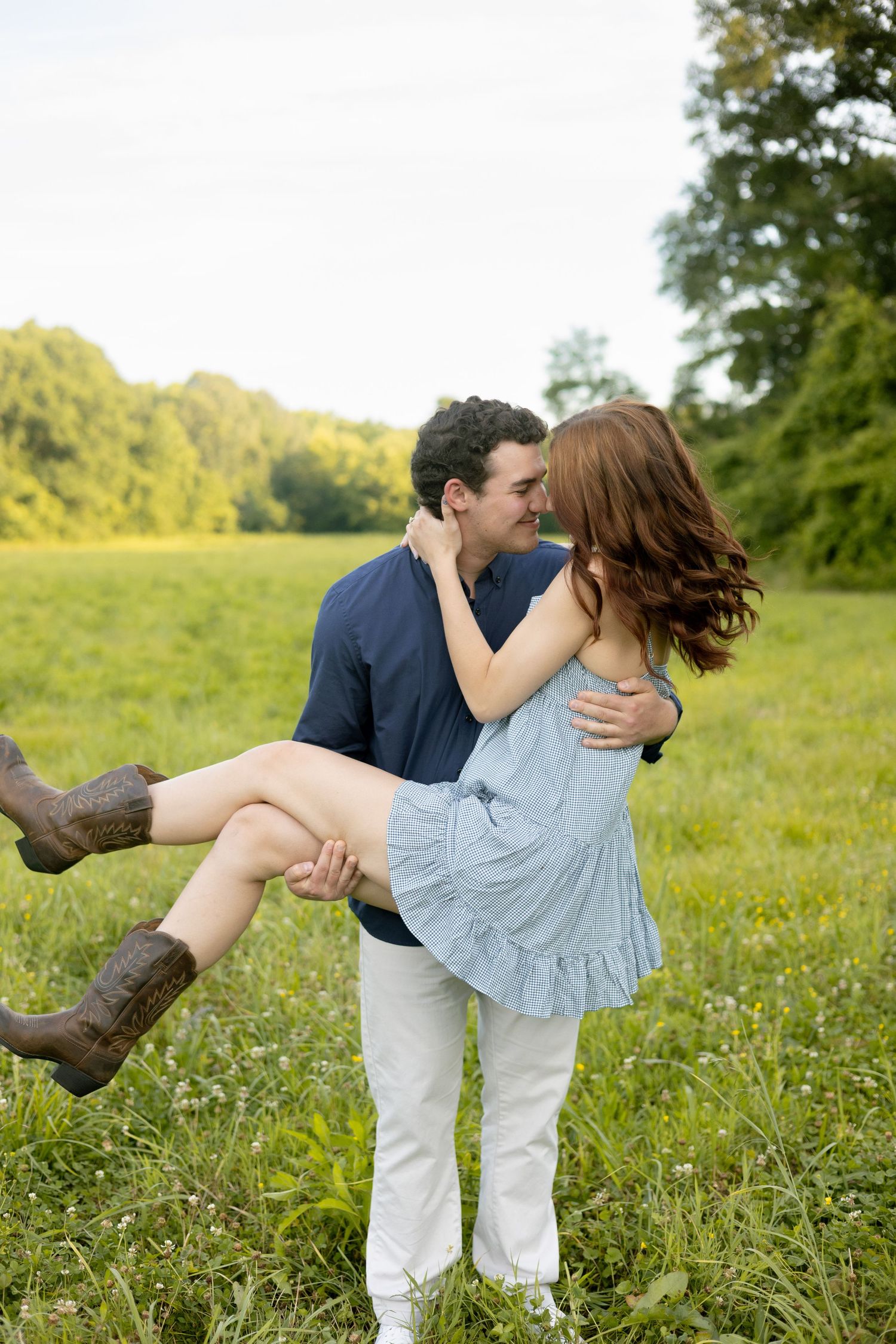 Couple laughing together in a green meadow, North Alabama engagement photographer