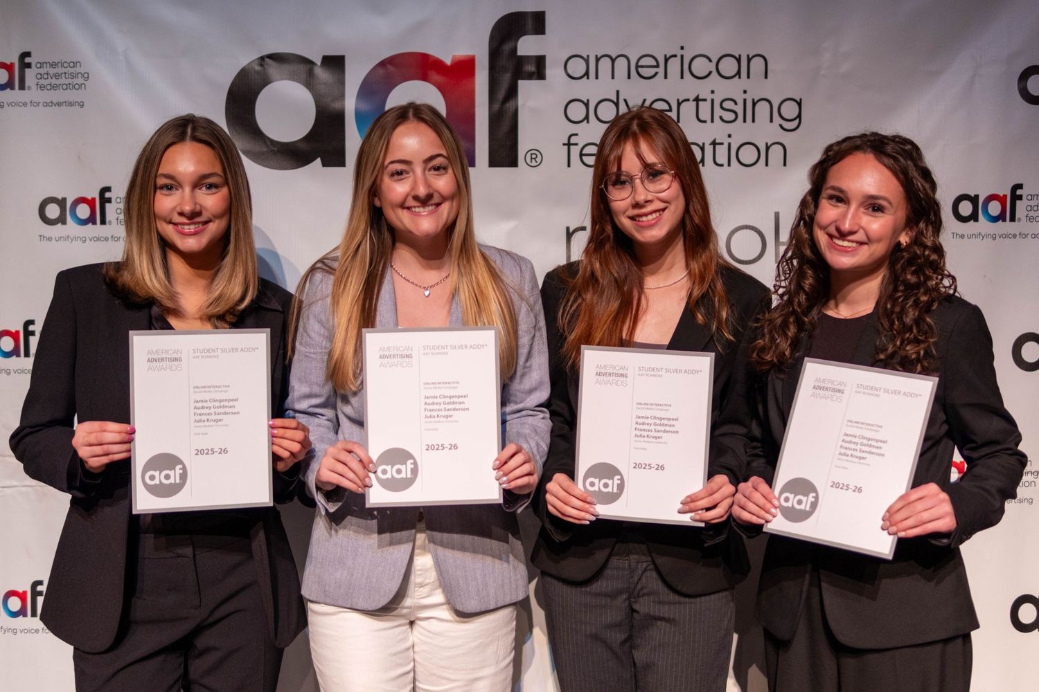 Four women pose together holding certificates at AAF American Advertising Federation awards backdrop.