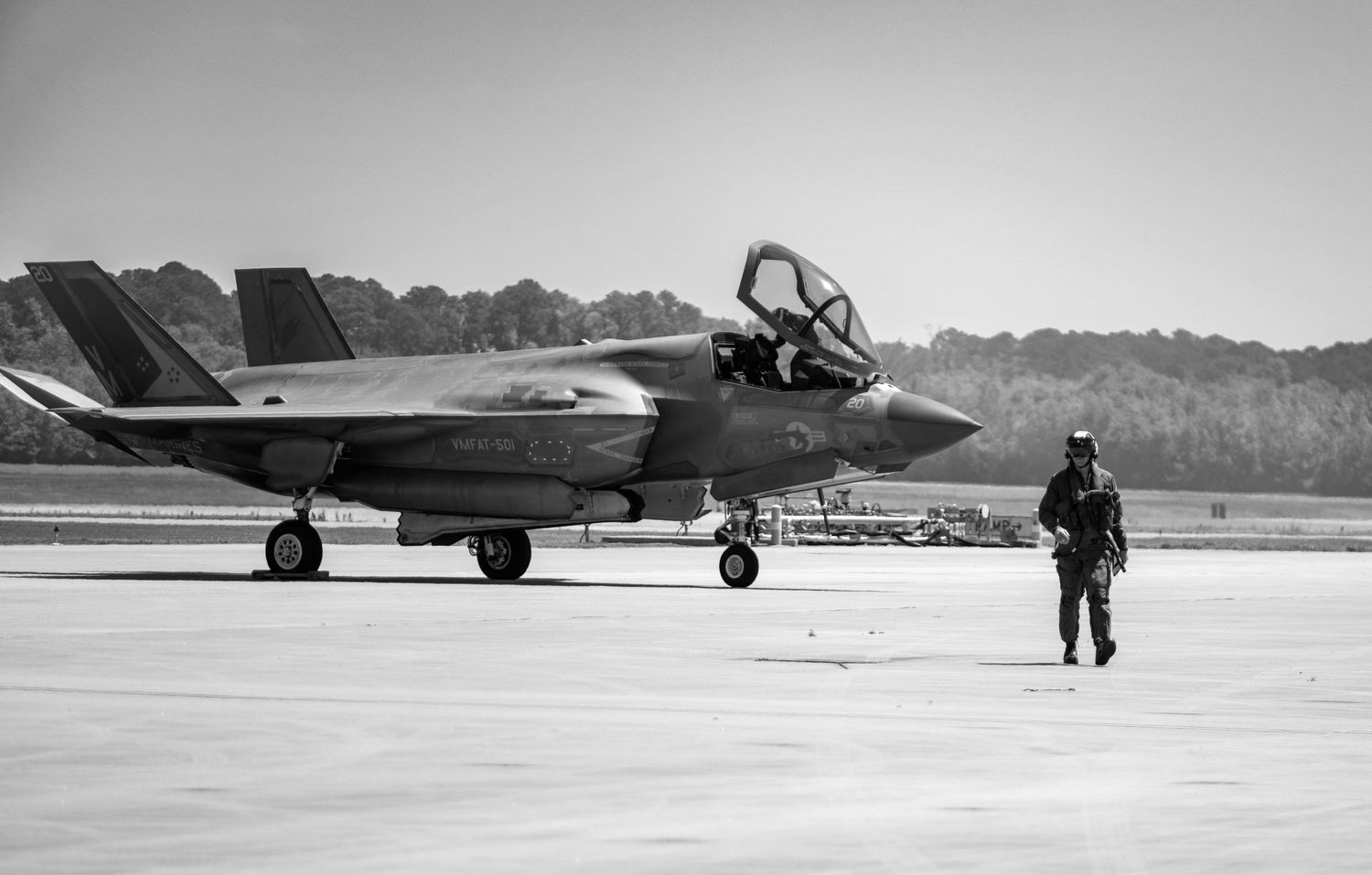 Black and white photo of an F-35 fighter jet taxiing with a crew member walking nearby.