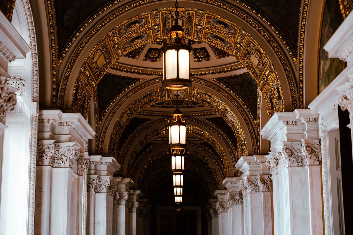 Ornate corridor with arched gilded ceilings and elegant lanterns inside the Library of Congress.