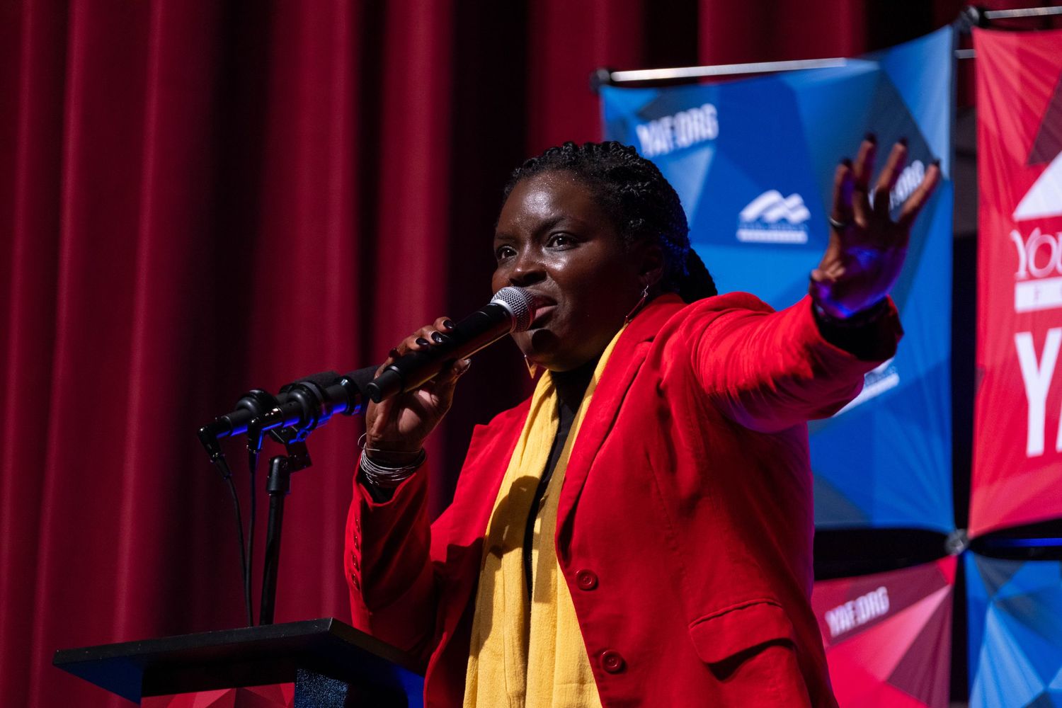 Female speaker gesturing passionately at microphone at YAF.org conservative youth conference.