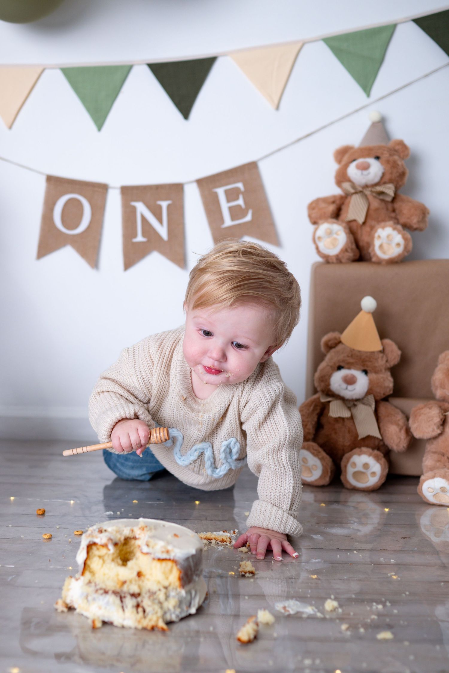 Messy baby boy crawls toward smashed birthday cake during first birthday cake smash photoshoot.