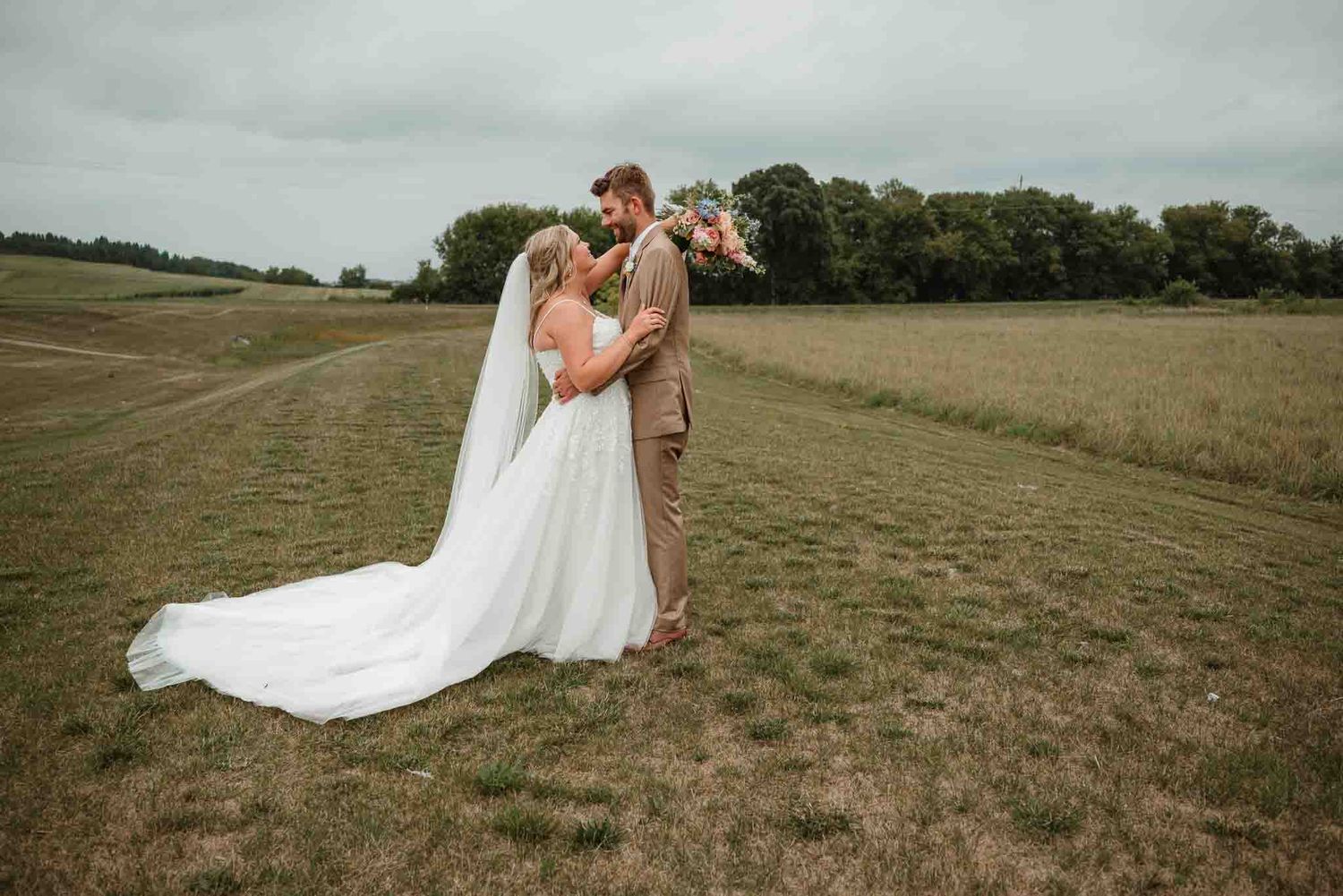 Couple laughing together in a field during their summer Minnesota wedding