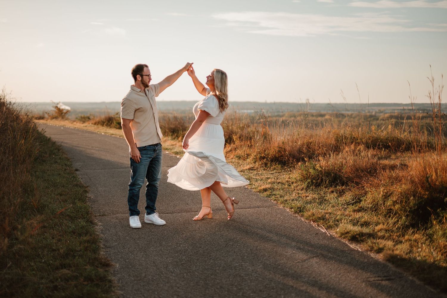 Couple twirling near prairie grass during a Minnesota sunrise engagement session