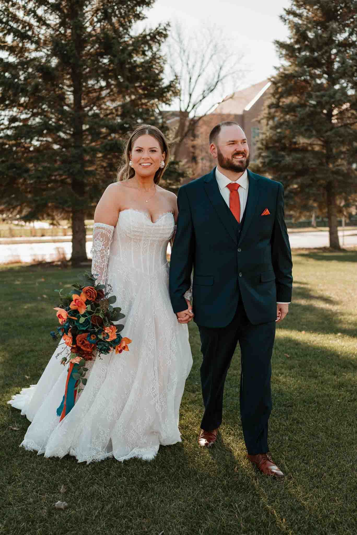 Newlyweds walking hand in hand during outdoor wedding portraits in November in North Dakota