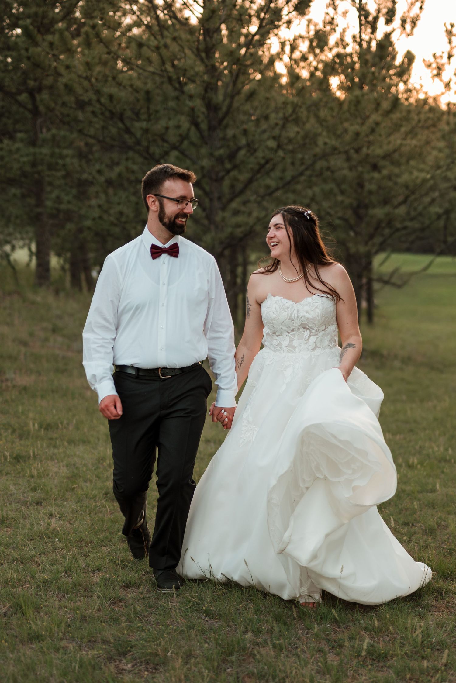 Couple walking through pines and grass in golden evening light in South Dakota