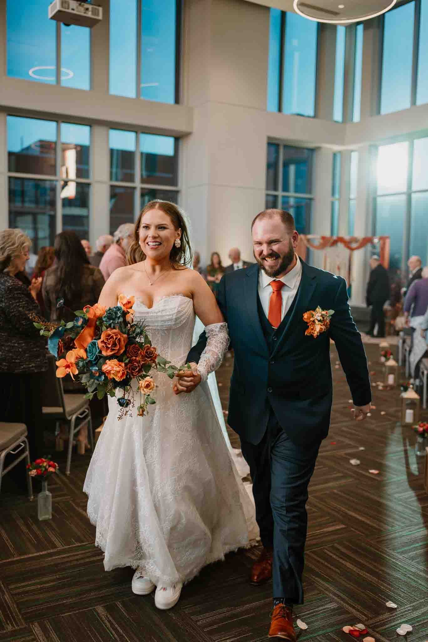 Newlyweds smiling as they walk back down the aisle after their wedding ceremony