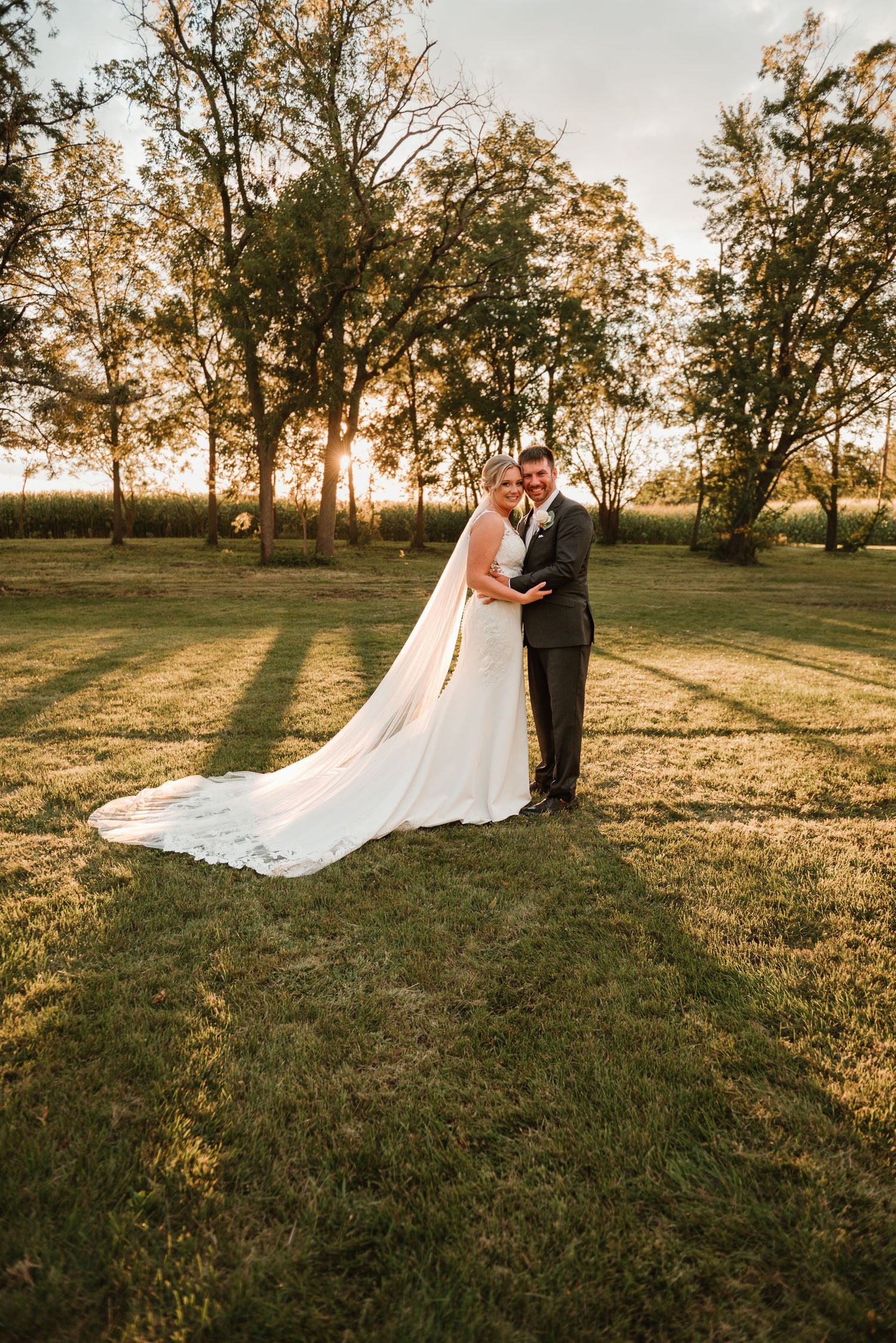 Couple hugging in a tree lined field during sunset photos on their farm in Minnesota