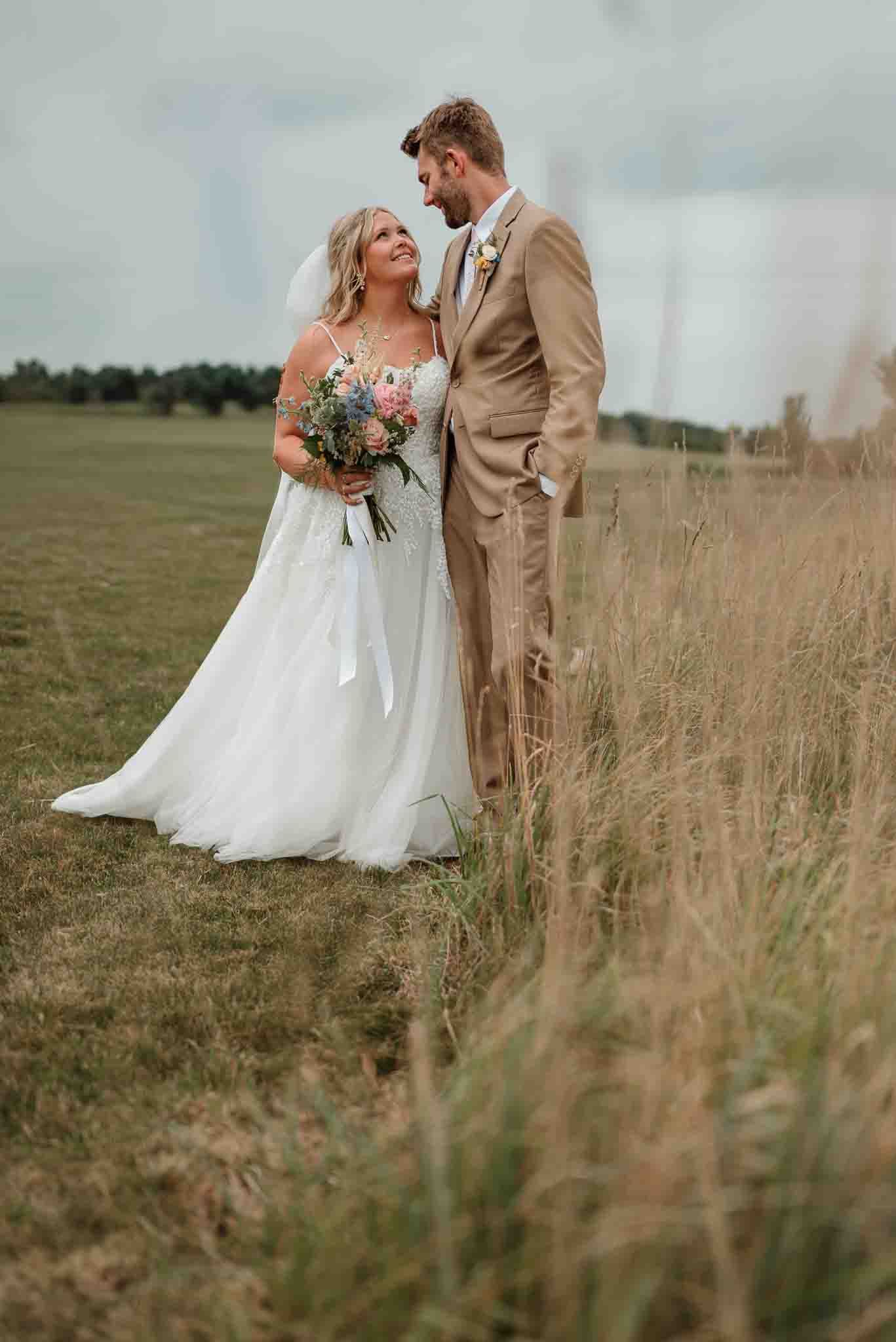 Bride and groom embracing in a sunlit field during golden hour at their Wisconsin wedding